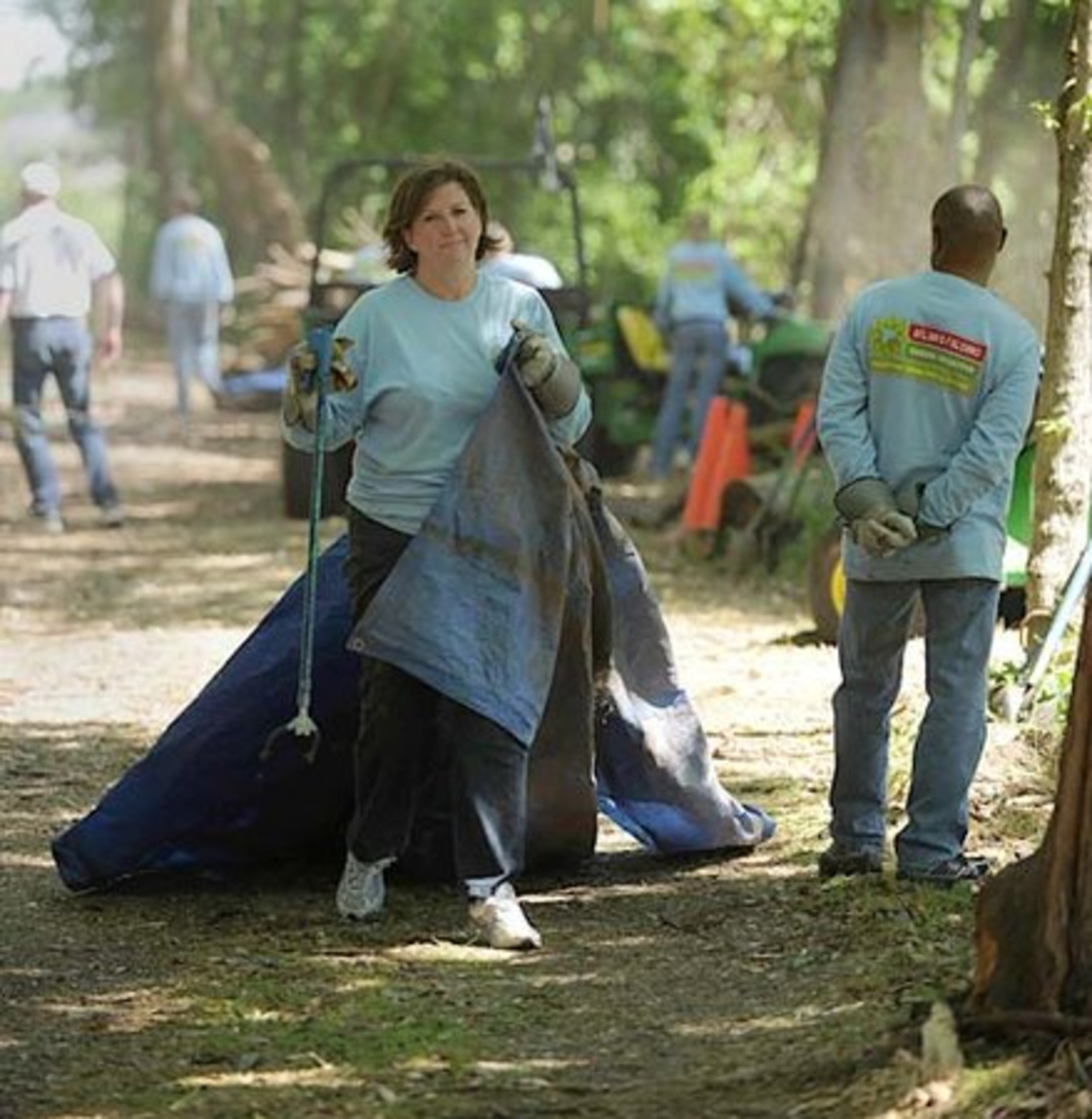 Karen Walters, of Dawsonville, drags a tarp as fellow employees of the Arthur M. Blank Family of Businesses volunteer in the community.