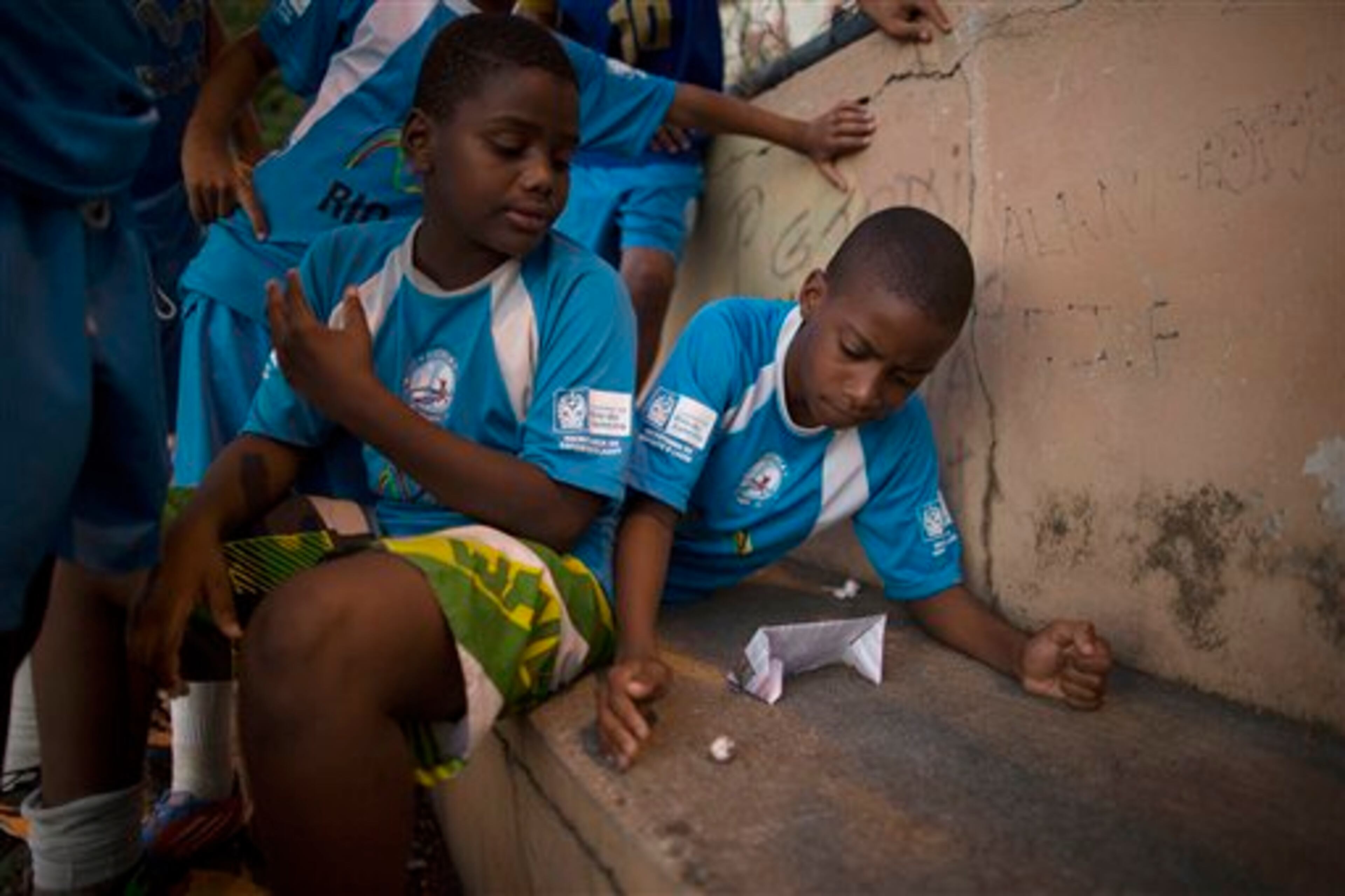 In this Wednesday, June 4, 2014 photo, kids play soccer using a ball and goalpost made of paper as they wait for their turn to play soccer in a court in the Mangueira slum of Rio de Janeiro, Brazil. Mangueira's few football pitches are constantly alive with residents of all ages honing their soccer skills. (AP Photo/Leo Correa)