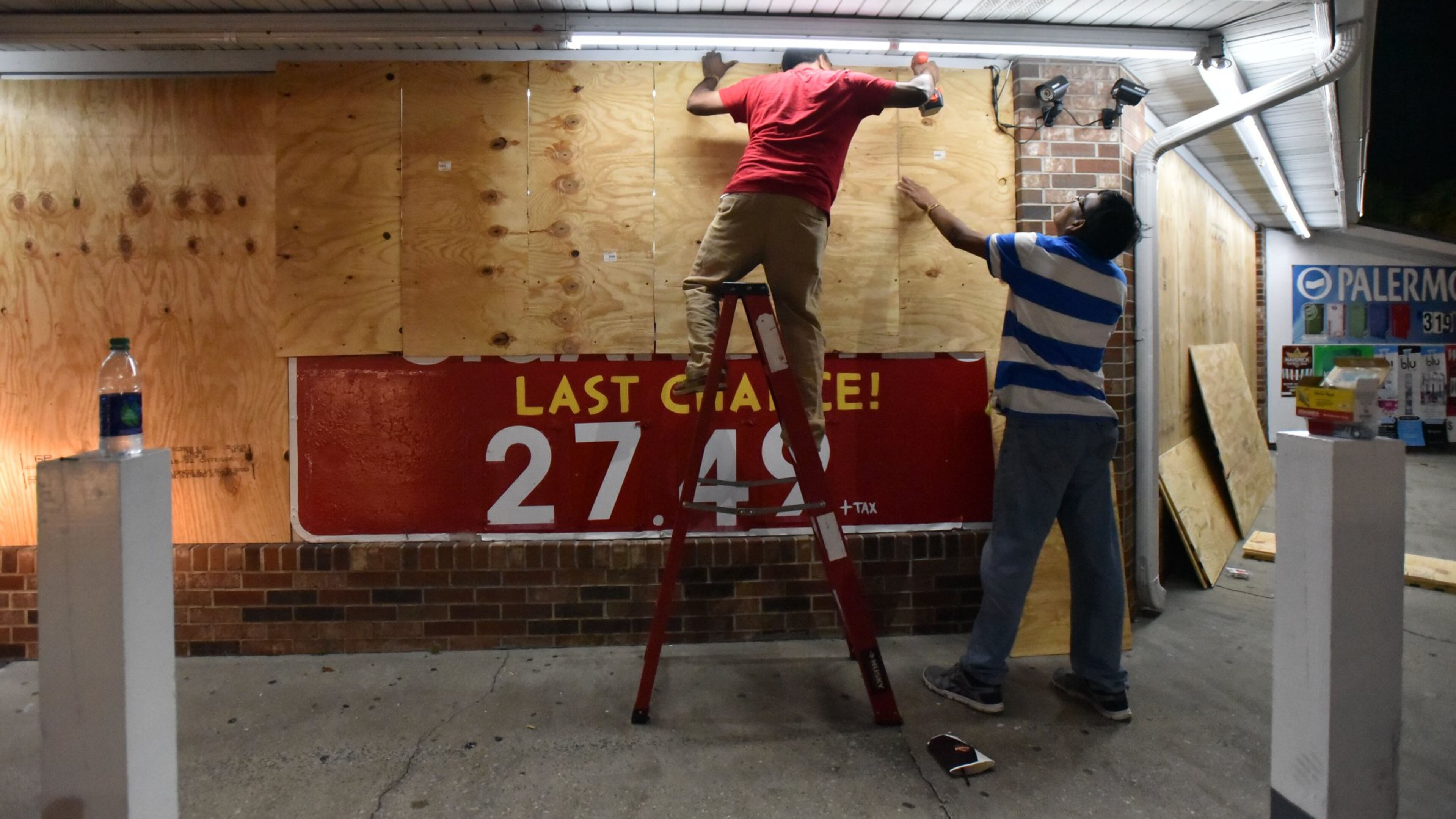 In Brunswick Thursday night, Jayesh Patel (left), owner, and Mahesh Patel board up their gas station ahead of Hurricane Matthew. HYOSUB SHIN / HSHIN@AJC.COM