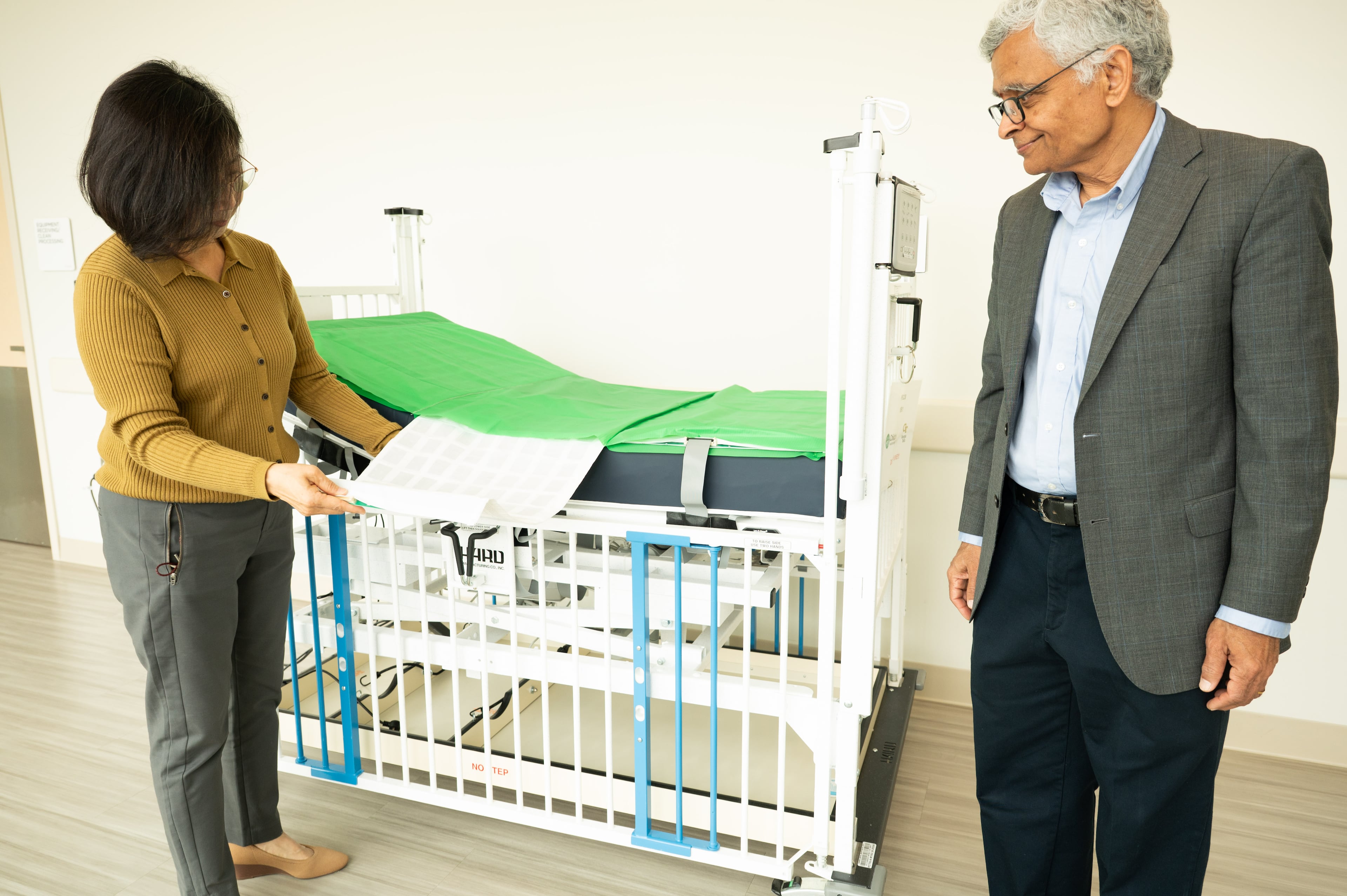 Park (left) and Jayaraman look over the "smart fabric" bedsheets now being used in a pilot program at Children's Healthcare of Atlanta. (Courtesy of Georgia Tech)