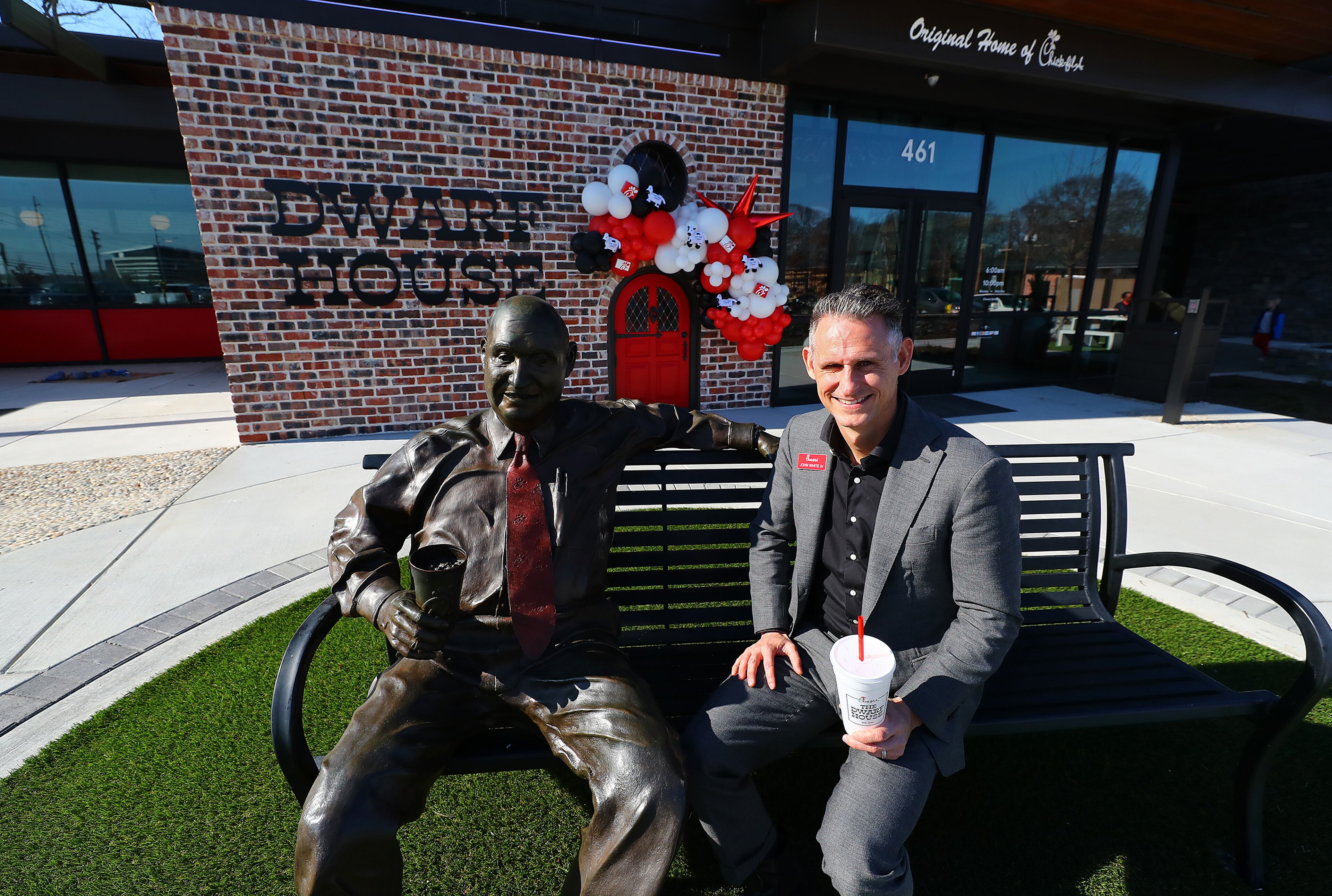 John White IV, grandson of S. Truett Cathy, sits beside a statue of his grandfather during a break from giving a tour of the newly renovated Dwarf House, the first of Truett Cathey’s restaurants. The original building was only 512 square feet, which is why Cathy called it Dwarf House, while the new renovation expands it to 10,643 square feet while preserving much of it's past. “Curtis Compton / Curtis.Compton@ajc.com”`