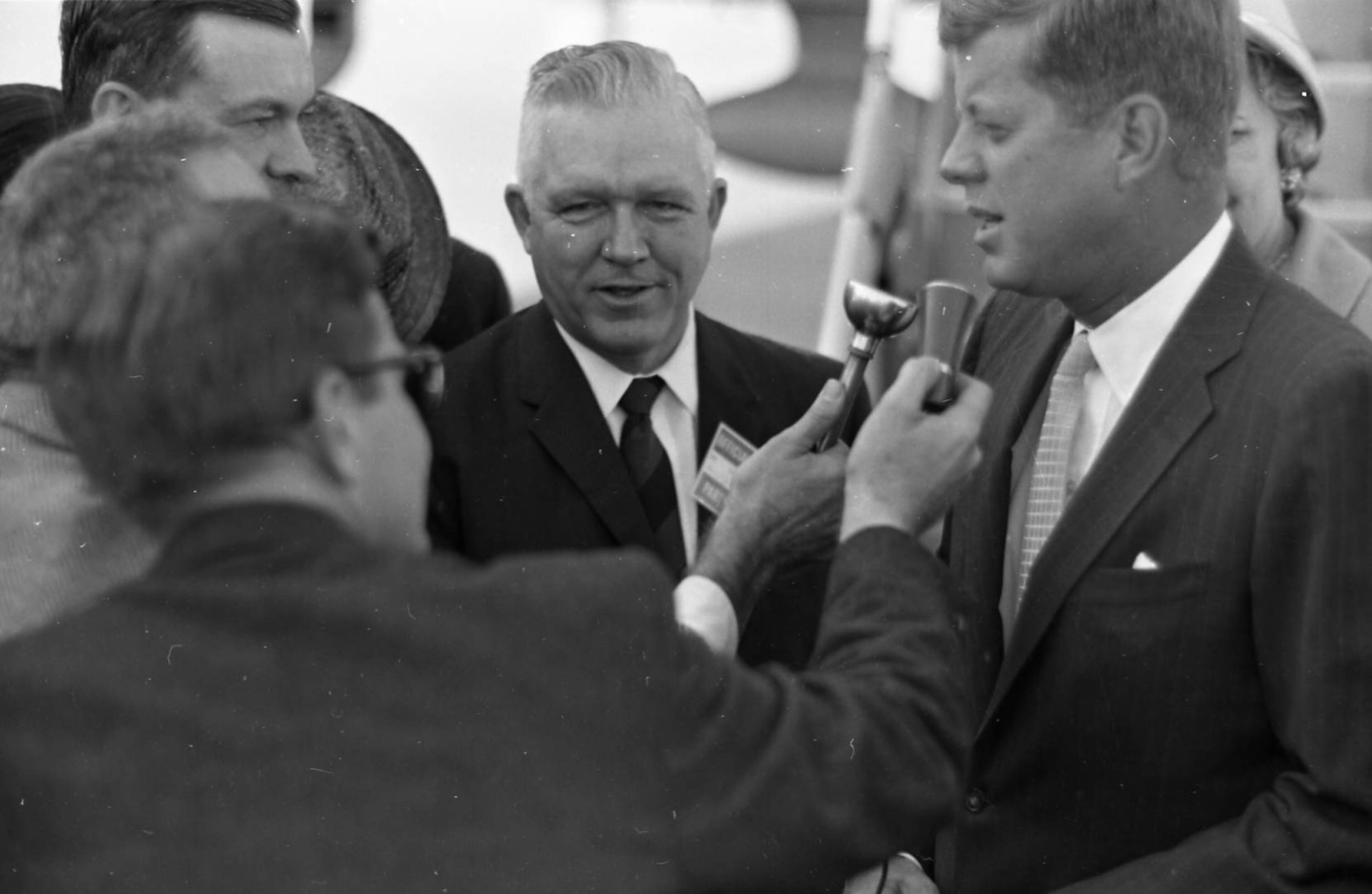 A gaggle of reporters surrounds Kennedy after he exits the plane.