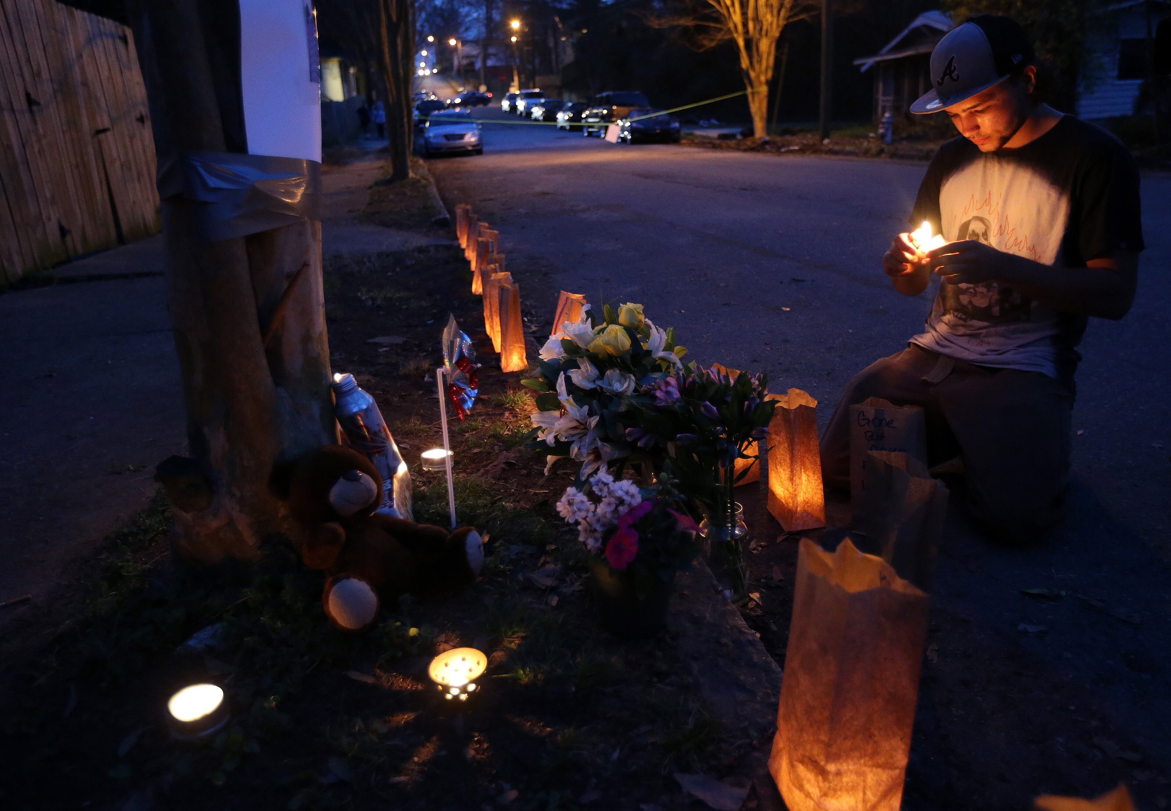 Christian Malcolm lights a candle while setting up a memorial to Kelcey "Skeet" Thornton at the spot in the Peoplestown neighborhood of Atlanta where he was shot and killed Sunday evening. Family, friends and neighbors held a vigil for the man Tuesday evening March 11, 2014. Police have not released a motive or details about the shooting.