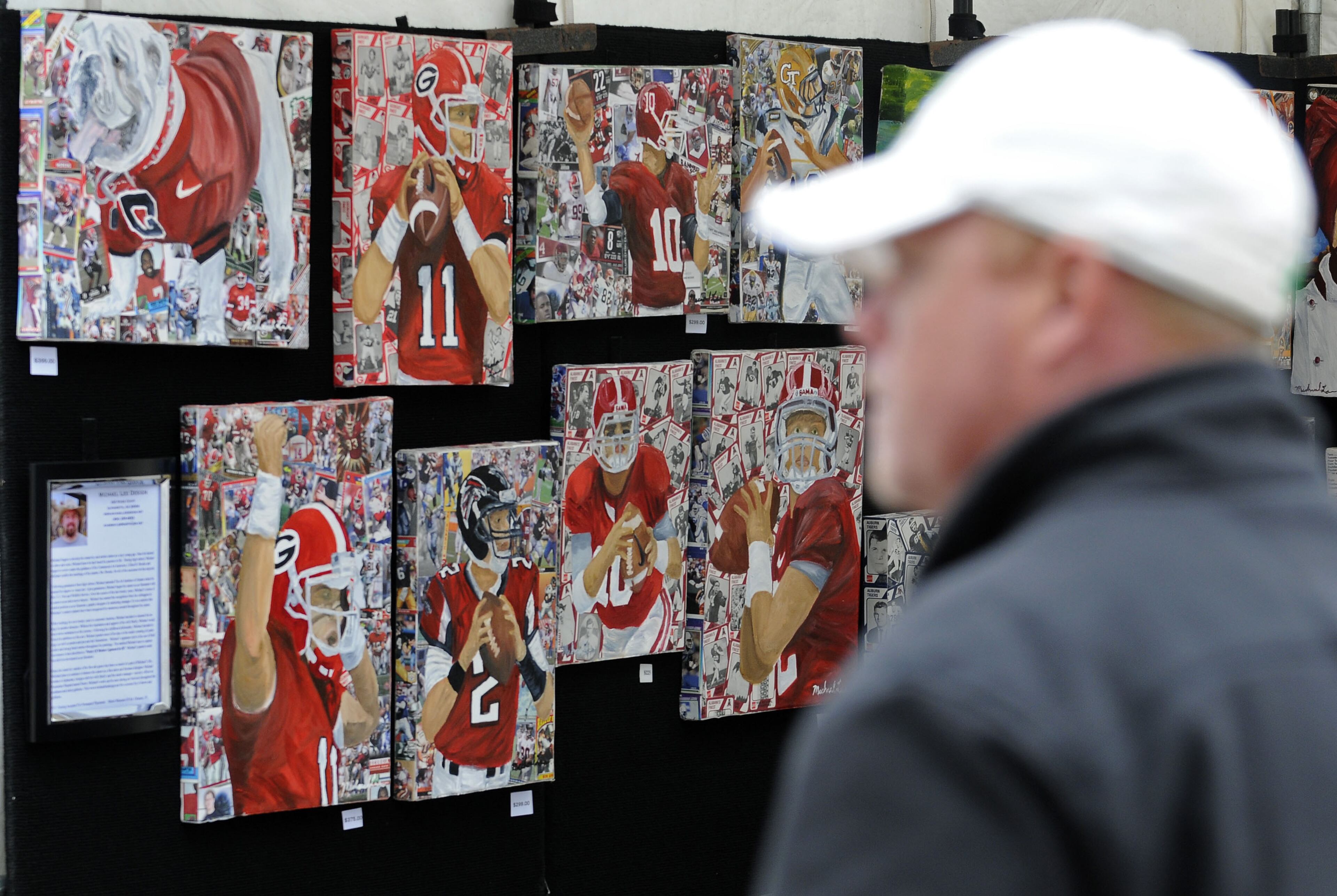 visitor walks by artist Michael Lee's paintings of Georgia athletes at the Smyrna Fall Jonquil Festival.