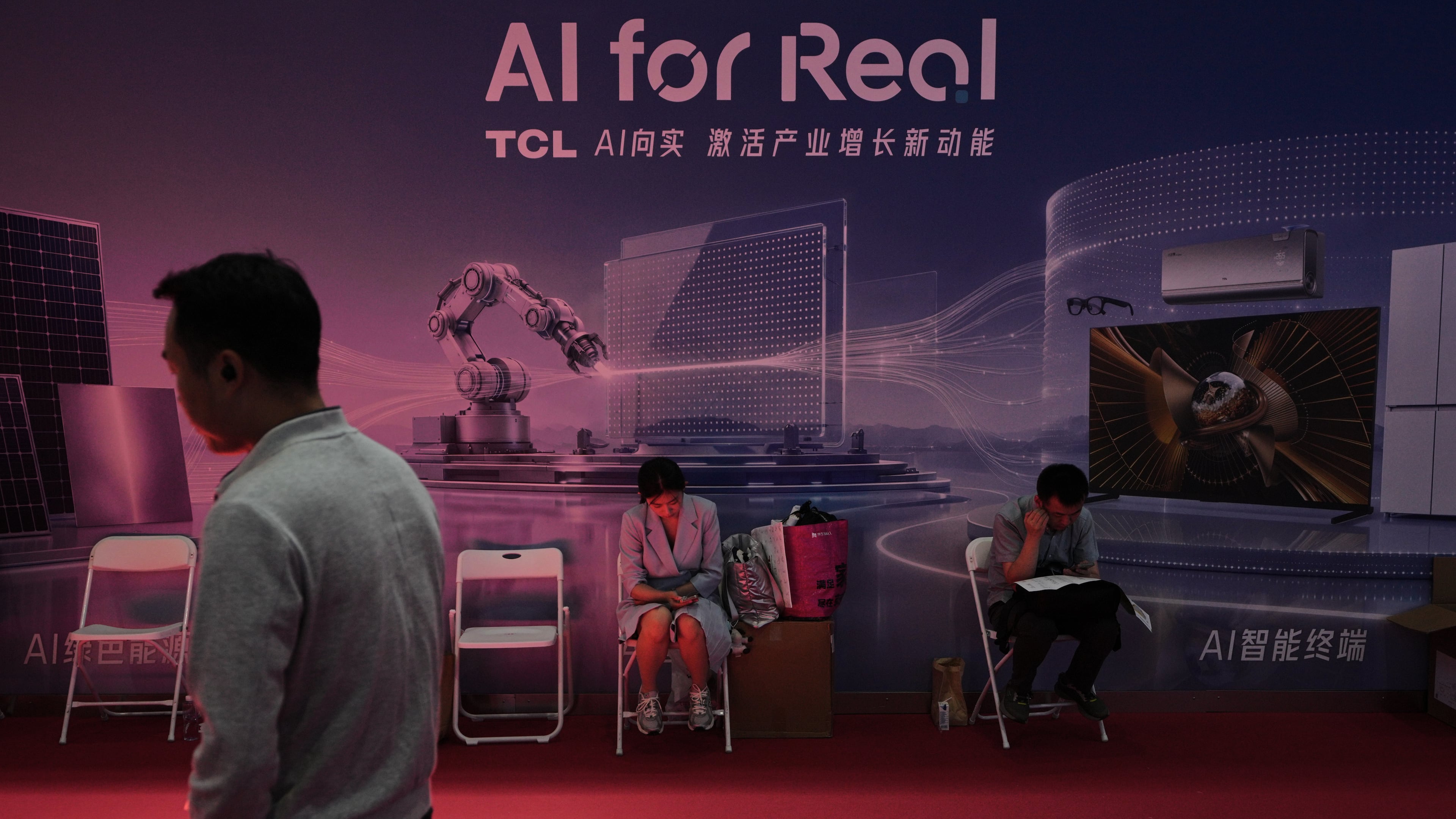A man walks by as workers rest near a board promoting Artificial Intelligence (AI) at the China International Supply Chain Expo in Beijing on June 25, 2026. (AP Photo/Andy Wong)