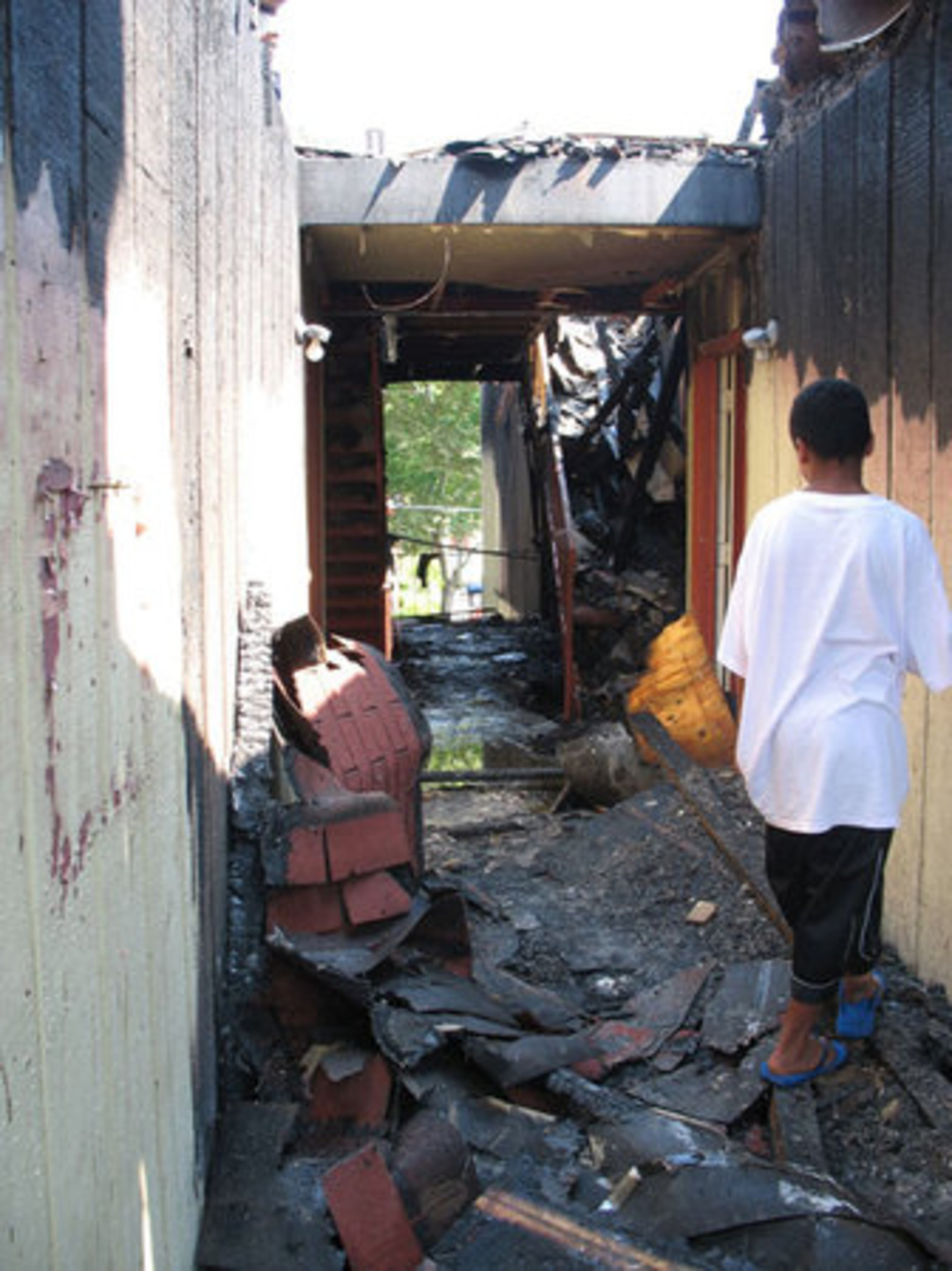 Daniel Ozuna, 14, stands in the breezeway of the burned out building at Magnolia Crossing. He's waiting for his family to go through what's left of their belongings.