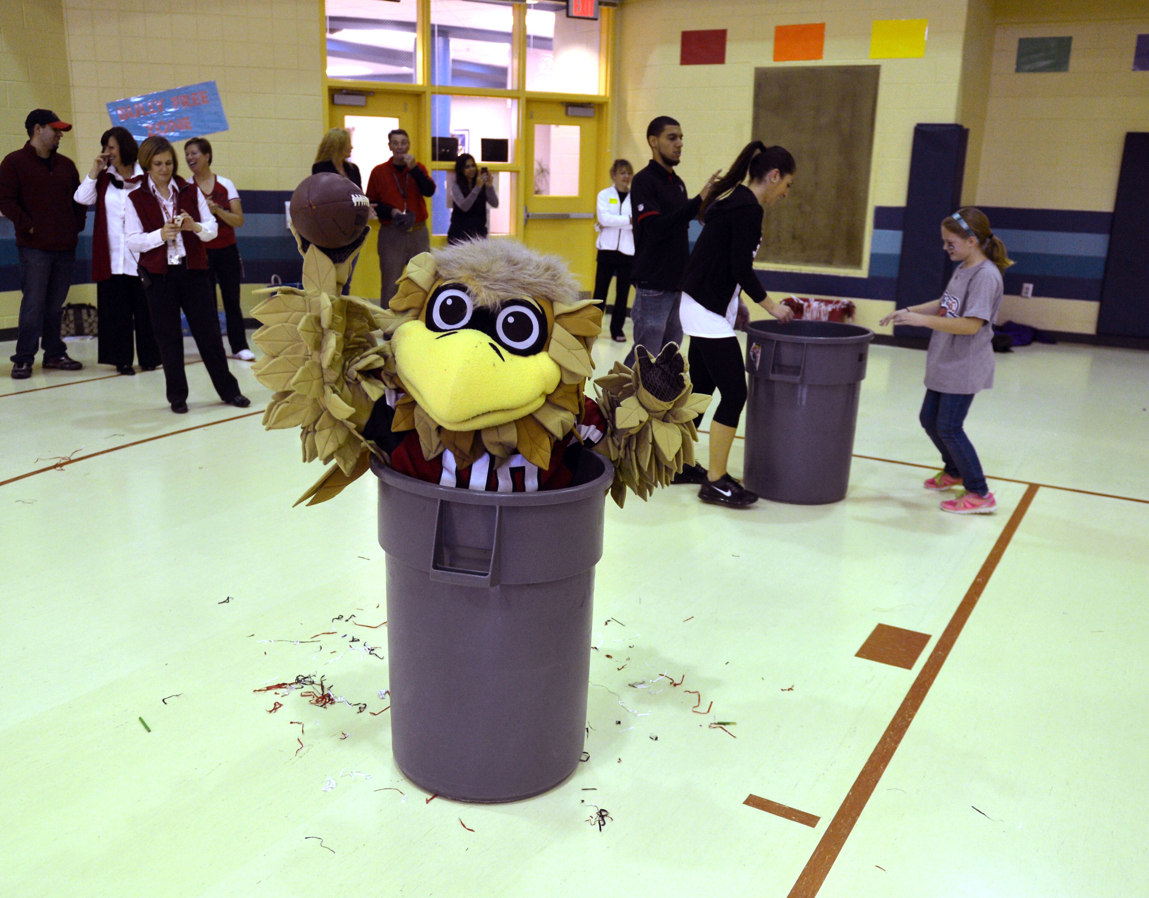 Freddie Falcon throws a football from a trash can during his visit to Shiloh Point Elementary.