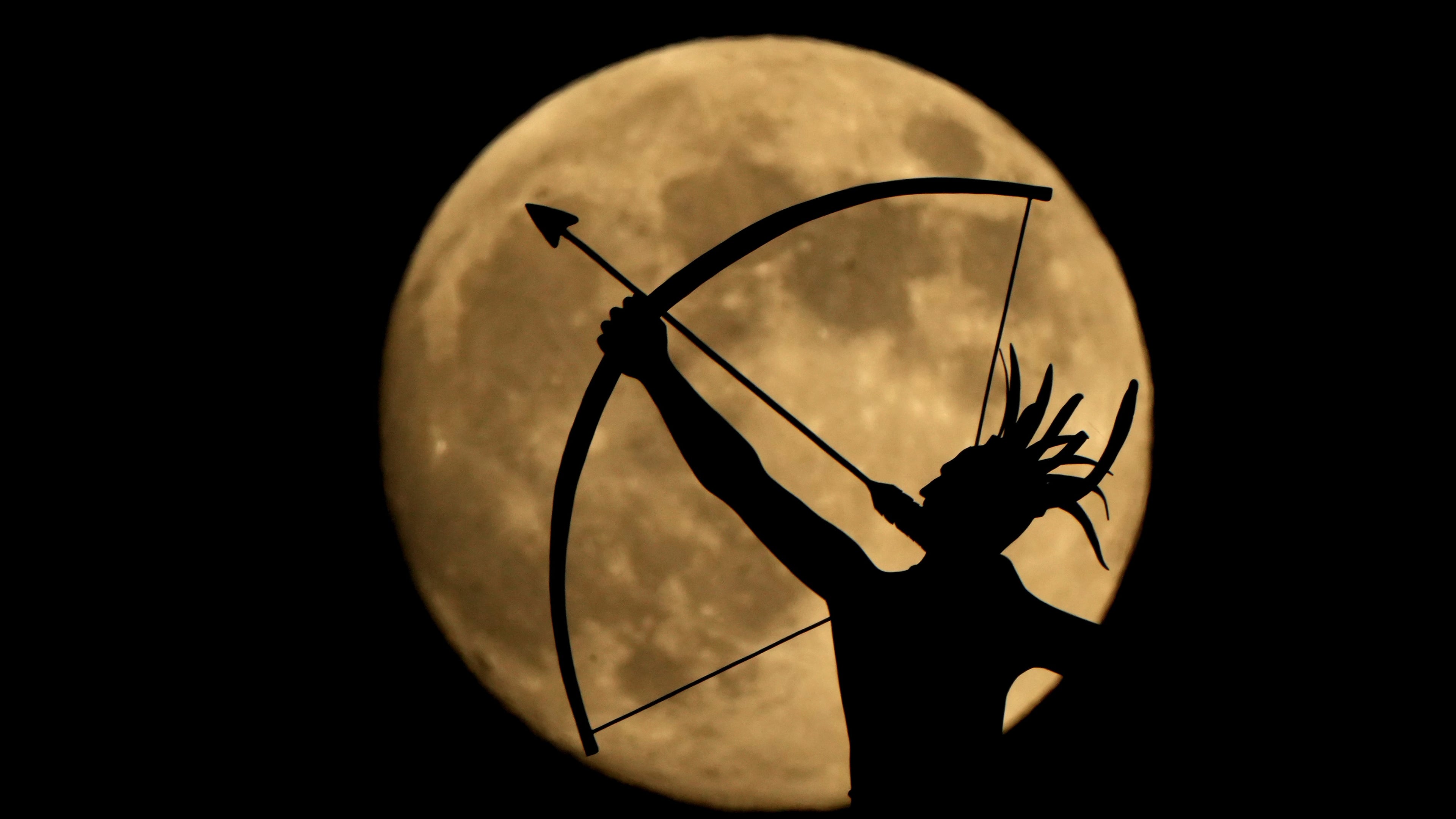FILE - The bronze sculpture titled "Ad Astra," depicting a Kansa warrior, perched atop the Kansas State Capitol dome, is silhouetted against the nearly full moon, Nov. 14, 2024, on the eve of the final supermoon of the year in Topeka, Kan. (AP Photo/Charlie Riedel, File)