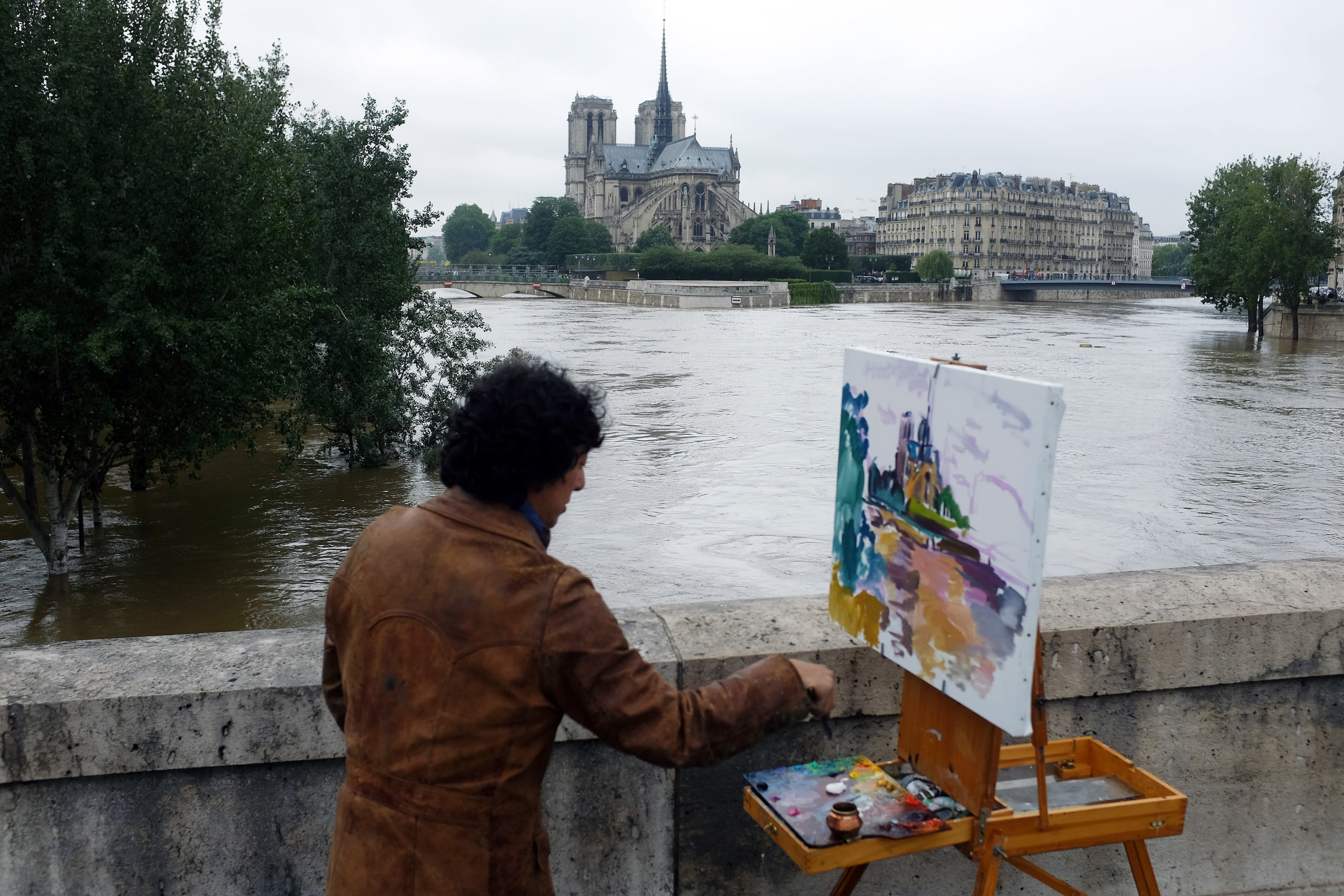 A man paints Notre Dame cathedral surrounded by the flooding Seine river in Paris, France Friday, June 3, 2016. Both the Louvre and Orsay museums were closed as the Seine, which officials said was at its highest level in nearly 35 years, was expected to peak sometime later Friday. (AP Photo/Jerome Delay)