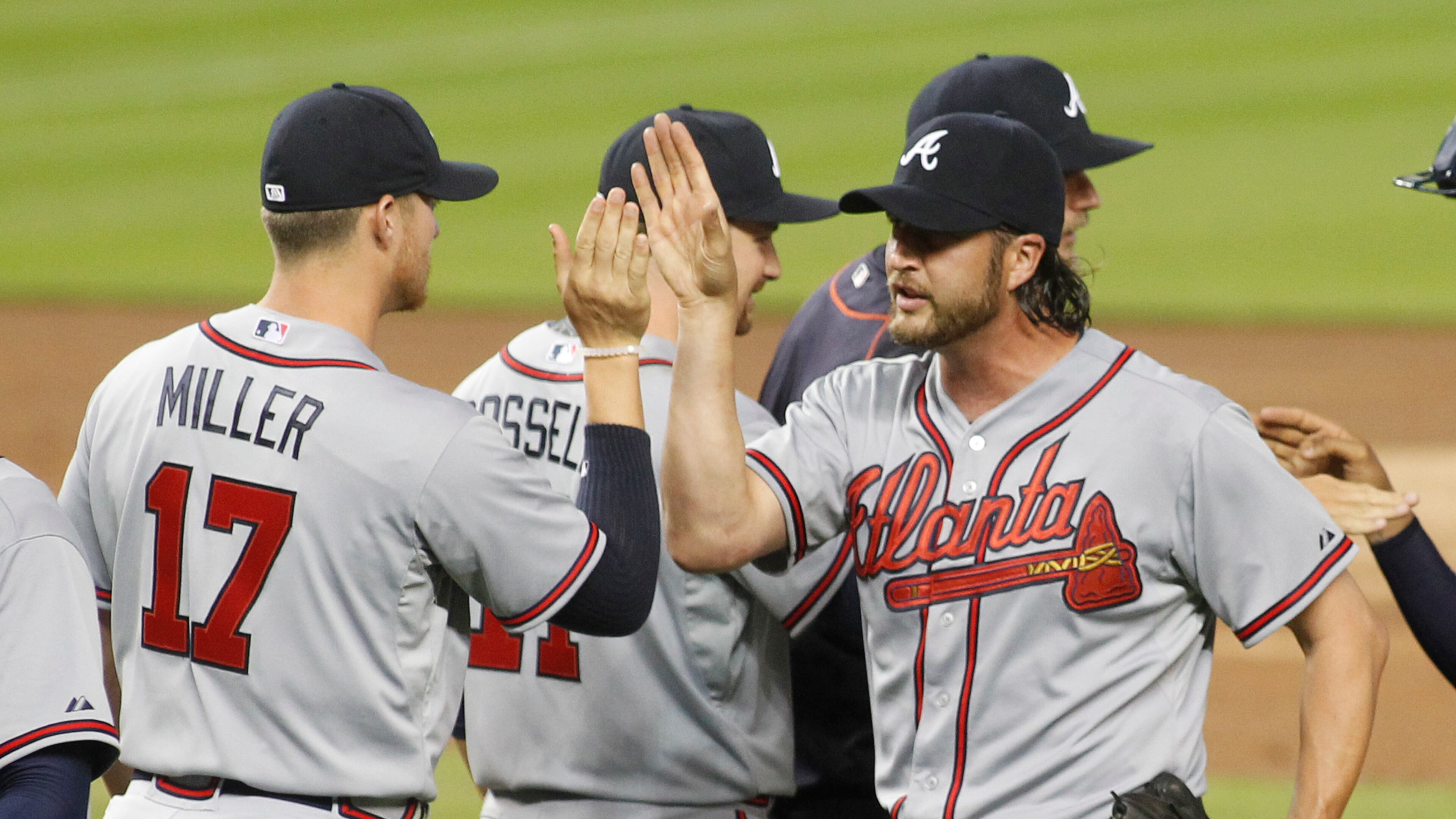 Atlanta Braves relief pitcher Jason Grilli, right, celebrates his save with teammates including pitcher Shelby Miller after the Braves defeated the Marlins 2-1 in their opening day baseball game in Miami, Monday, April 6, 2015. (AP Photo/Joe Skipper)