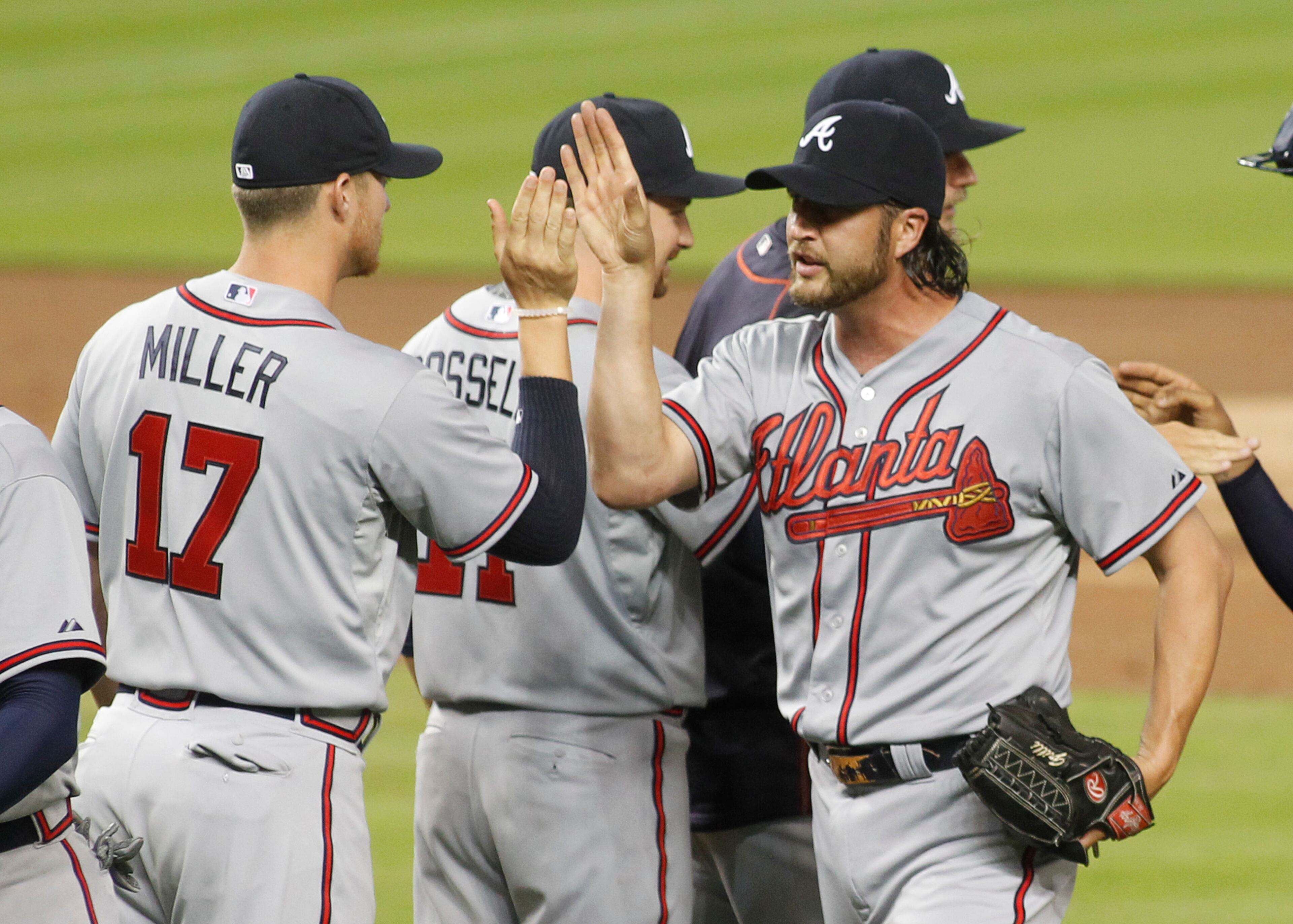 Atlanta Braves relief pitcher Jason Grilli, right, celebrates his save with teammates including pitcher Shelby Miller after the Braves defeated the Marlins 2-1 in their opening day baseball game in Miami, Monday, April 6, 2015. (AP Photo/Joe Skipper)