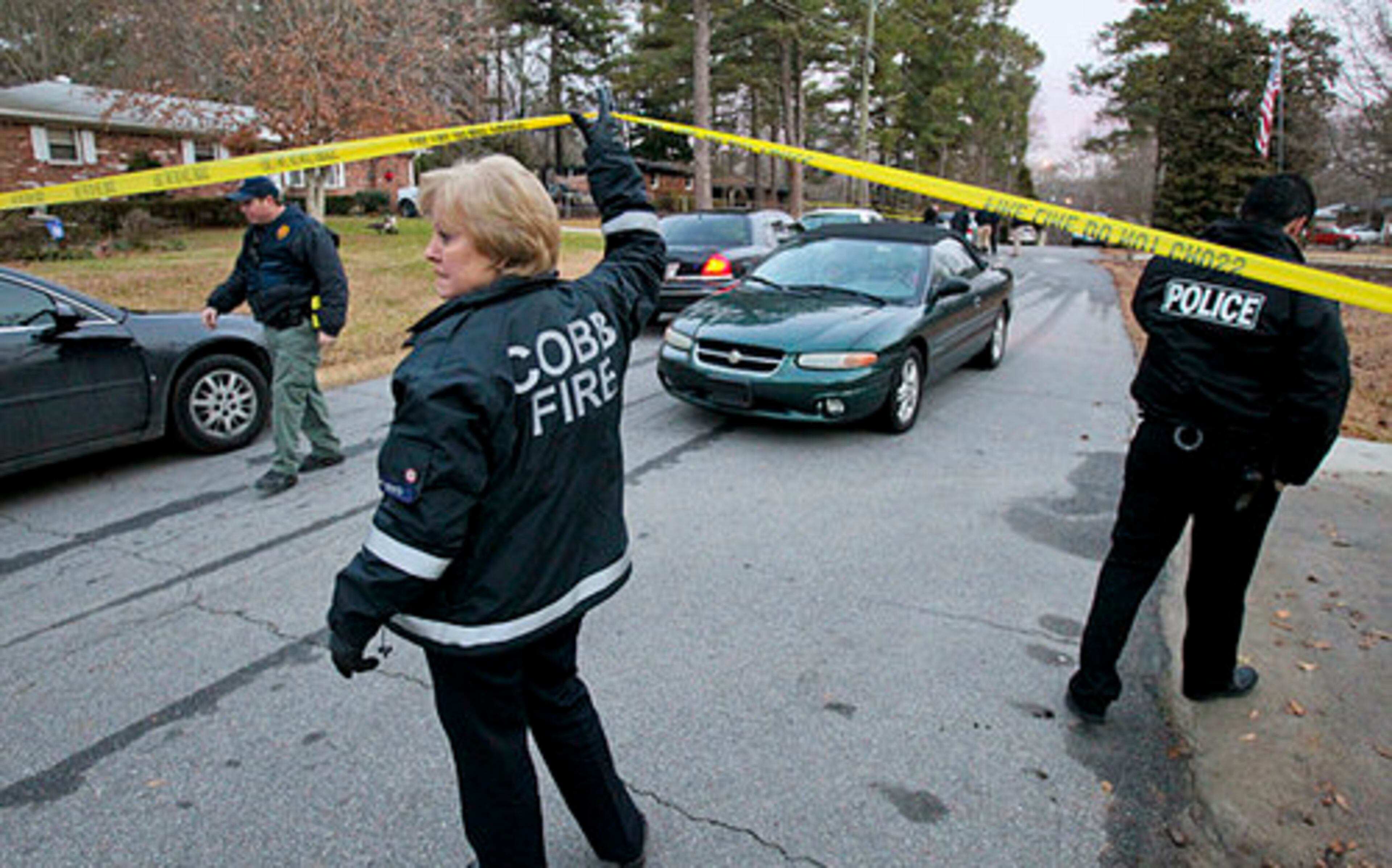 Cobb County fire Lt. Denell Boyd lifts up fire scene tape to allow neighbors to pass.