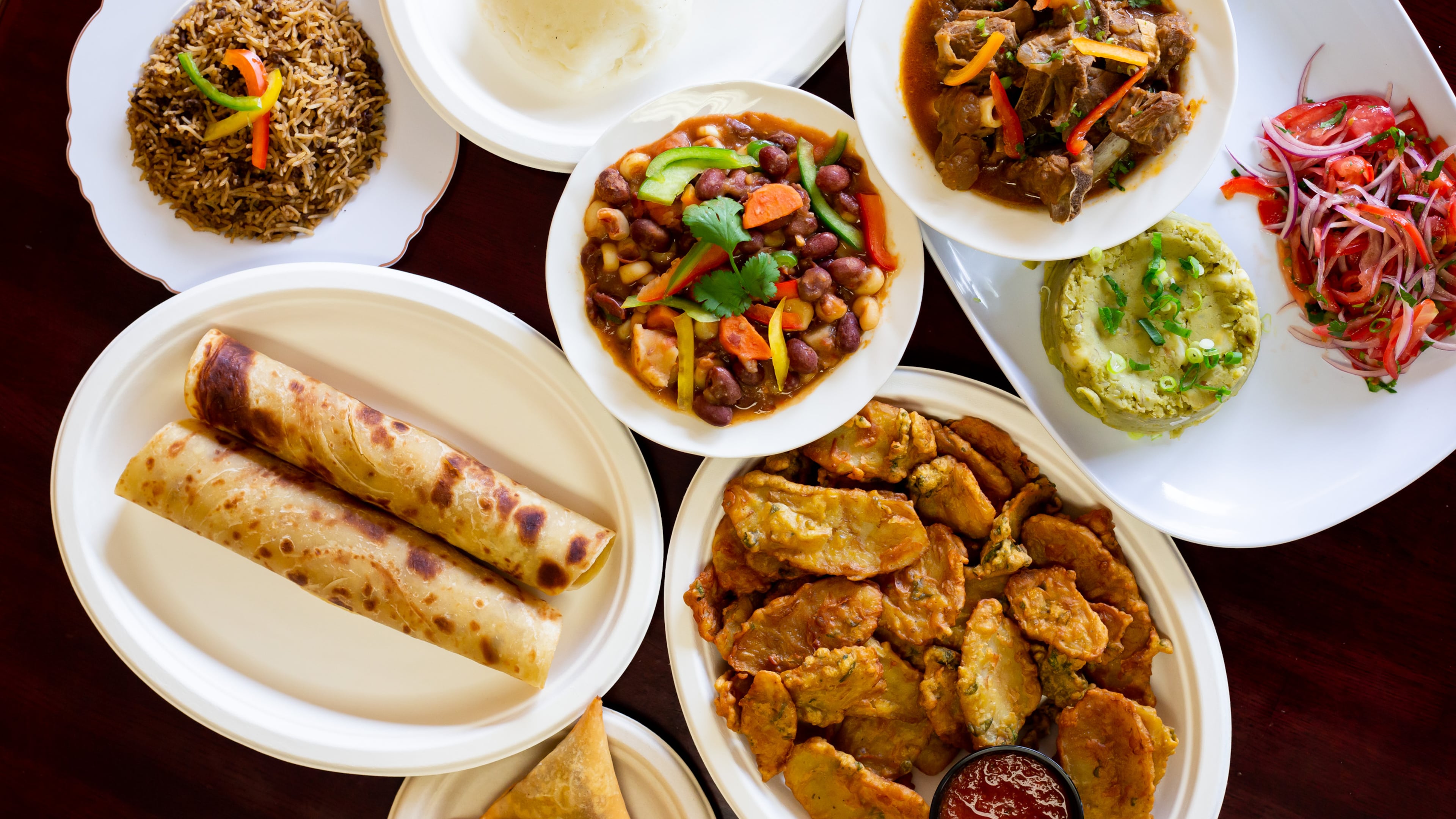 Jambo Grill offers traditional Kenyan dishes, including (clockwise from left) chapati, pilau, ugali, githeri, goat stew, kachumbari, irio, bhajias and beef samosa. Ryan Fleisher for The Atlanta Journal-Constitution