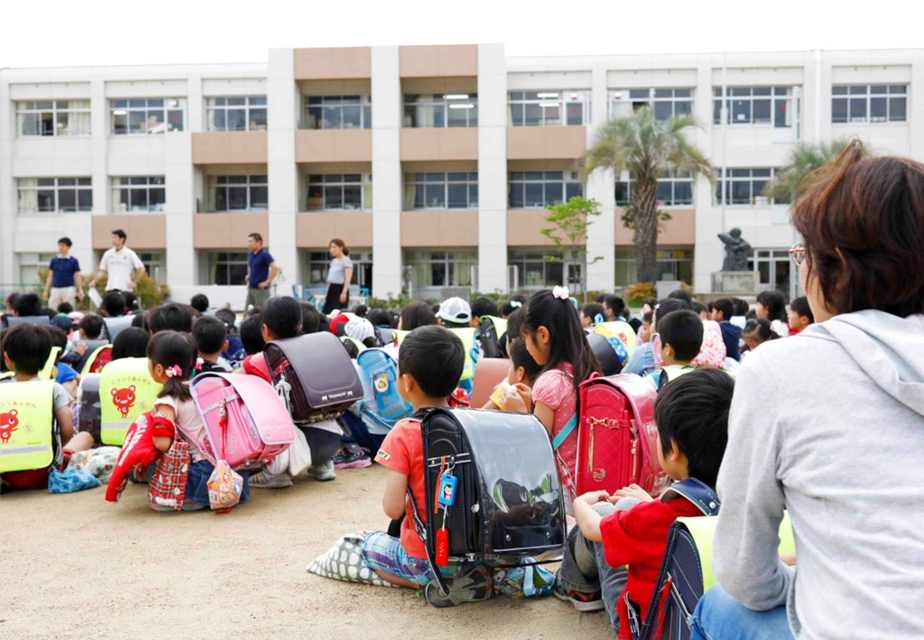 School children take shelter at schoolyard in Ikeda, Osaka, following an earthquake Monday, June 18, 2018. A strong earthquake has shaken the city of Osaka in western Japan. There are reports of scattered damage including broken glass and concrete. (Takaki Yajima/Kyodo News via AP)