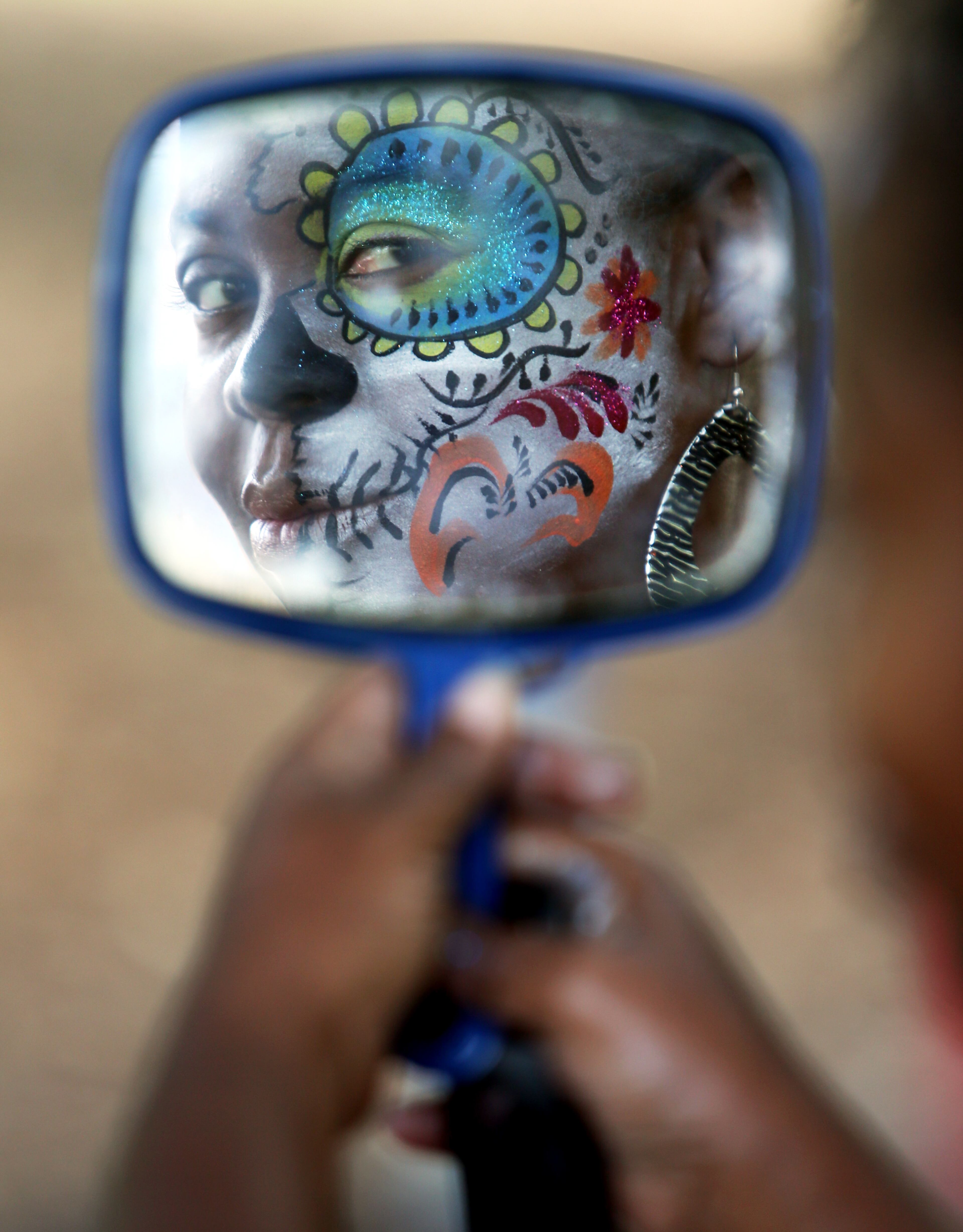 Monica Glover, Atlanta, checks out her skinzart creation in a mirror while painting faces at the Festival Peachtree Latino on Sunday.