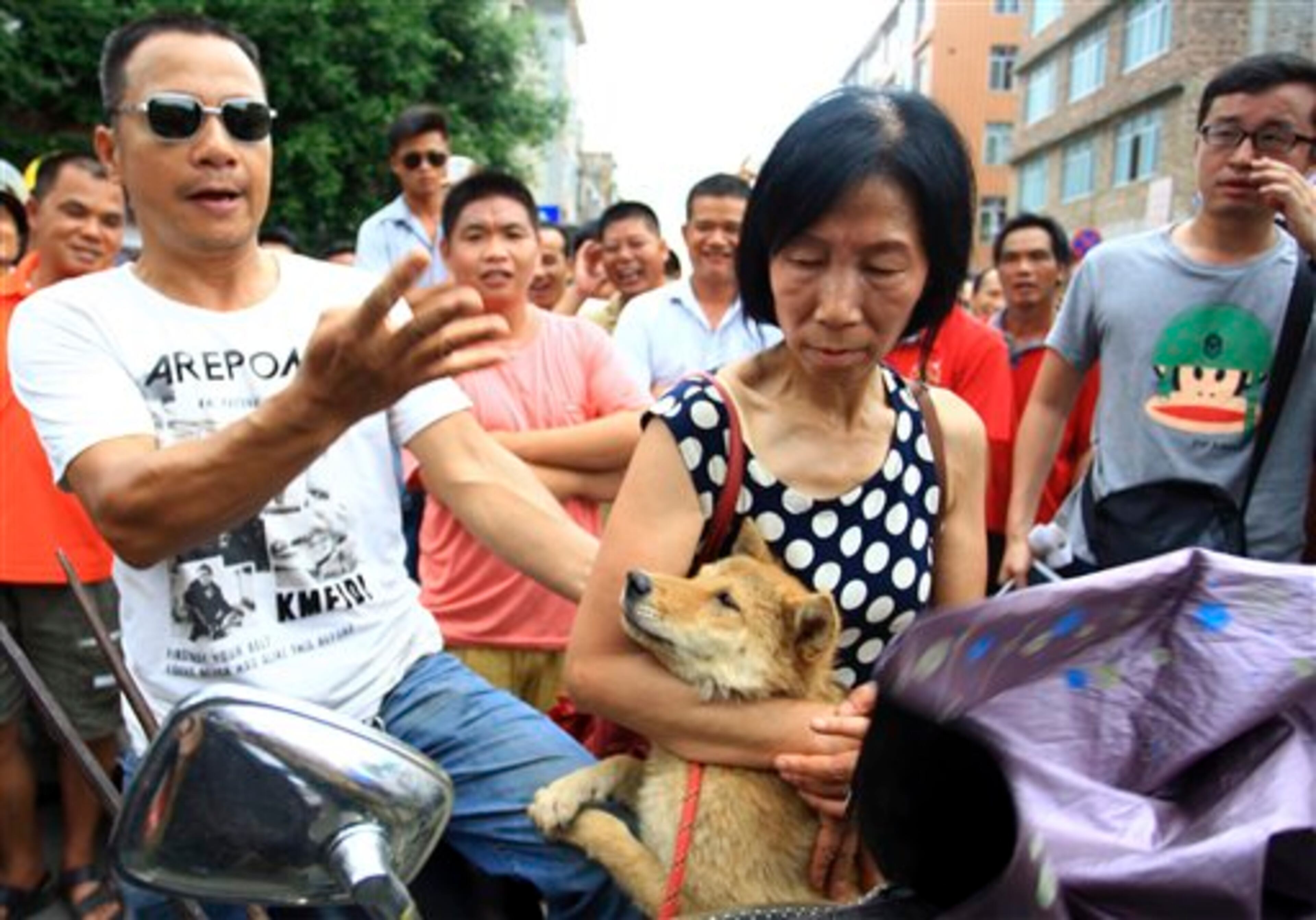An animal rights activist, center holds on to a dog as a vendor demands RMB400 or $64 for the dog in Yulin city in southwest China's Guizhou province Friday June 20, 2014. Animal rights activists have converged on the city in a bid to end a annual summer solstice festival in which thousands of dogs are slaughtered for food. (AP Photo) CHINA OUT