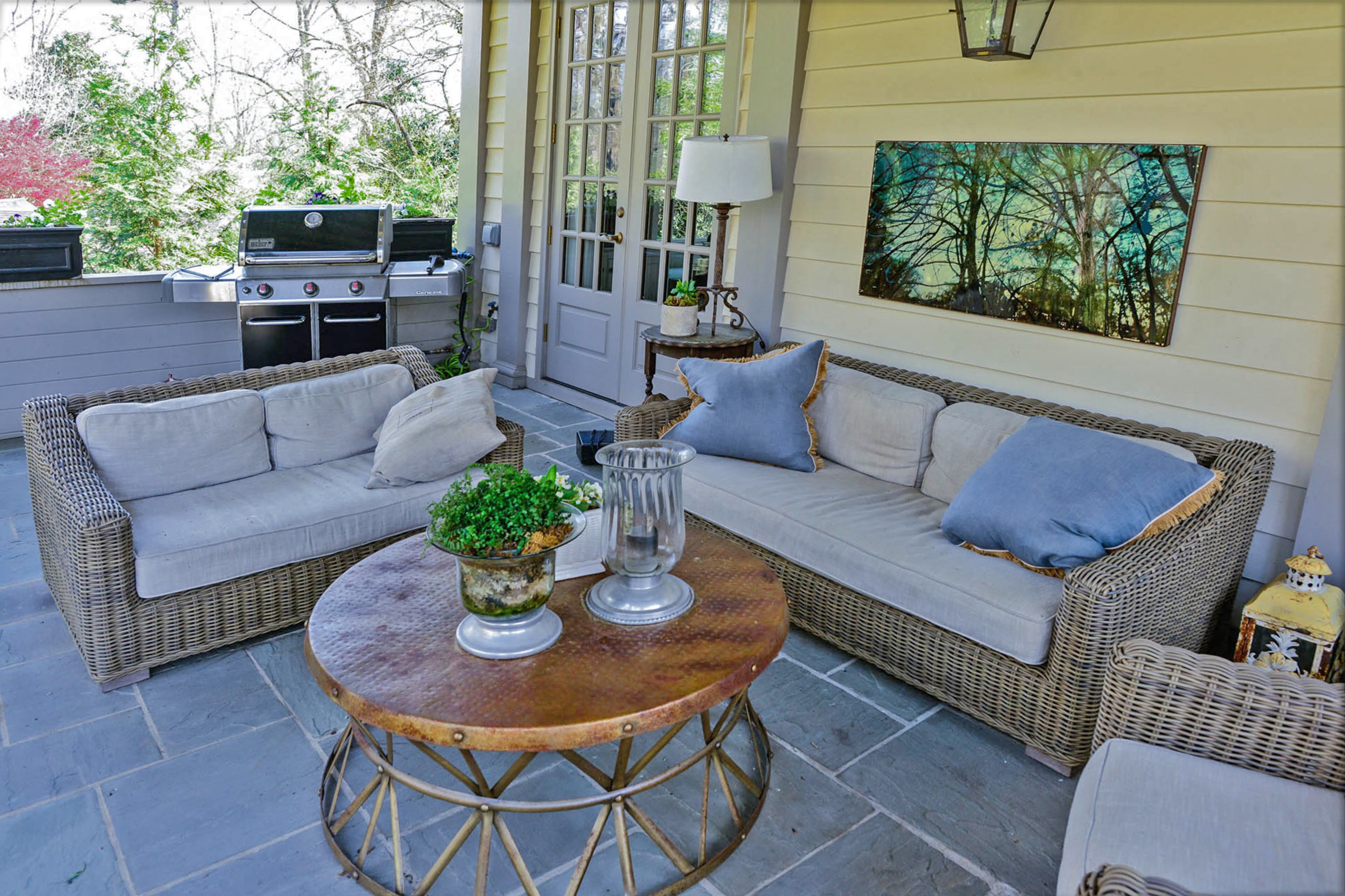 On the covered porch, Dina Woodruff decorated with an image transfer on reclaimed metal by her son, Wood Adamson, and iron coffee table from Peridot.