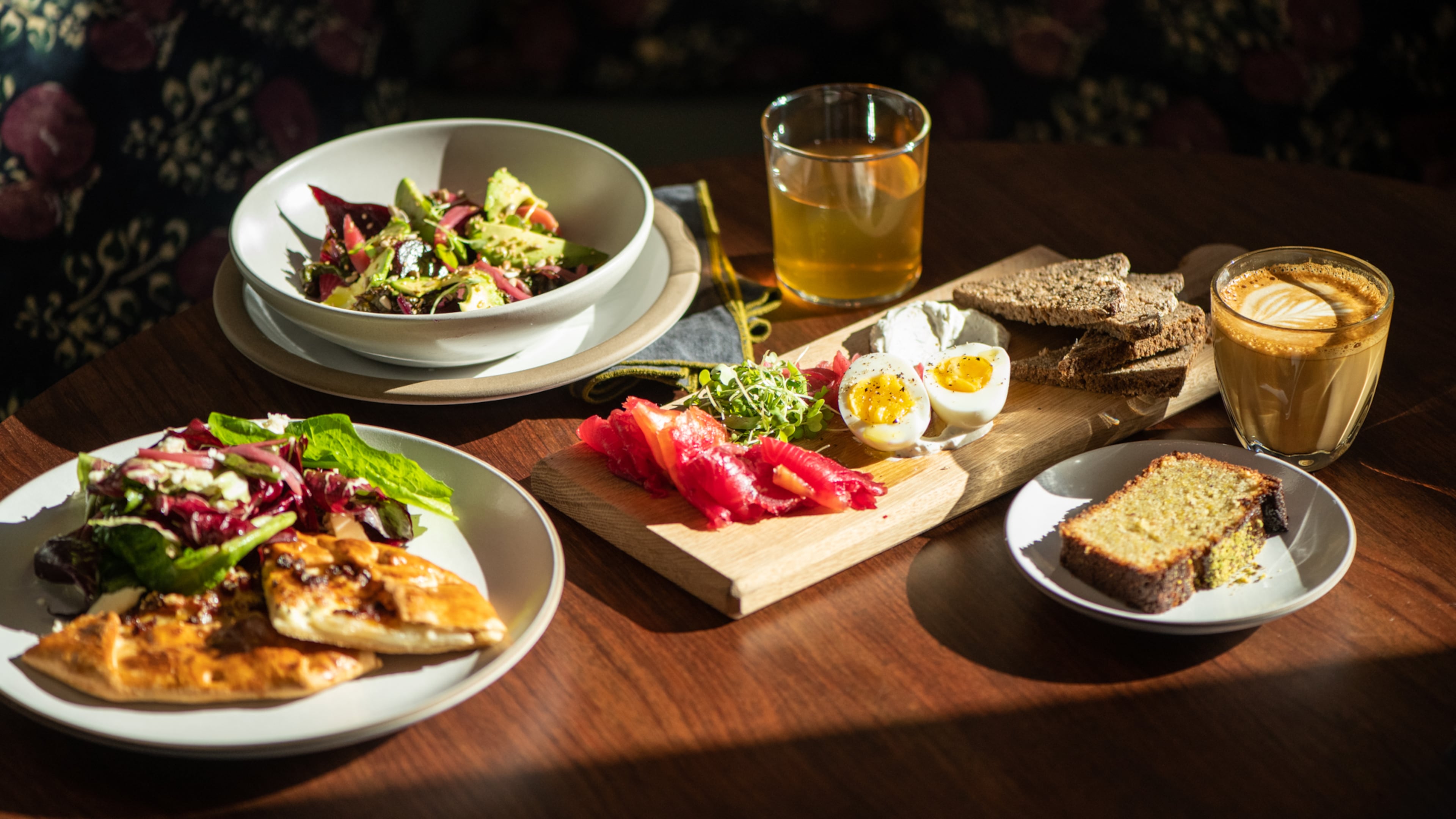 Le Bon Nosh's pear galette (left), beet salad (upper left), beet-cured salmon (center) and pistachio cake (lower right) are shown with tea and latte. (Mia Yakel for The Atlanta Journal-Constitution)