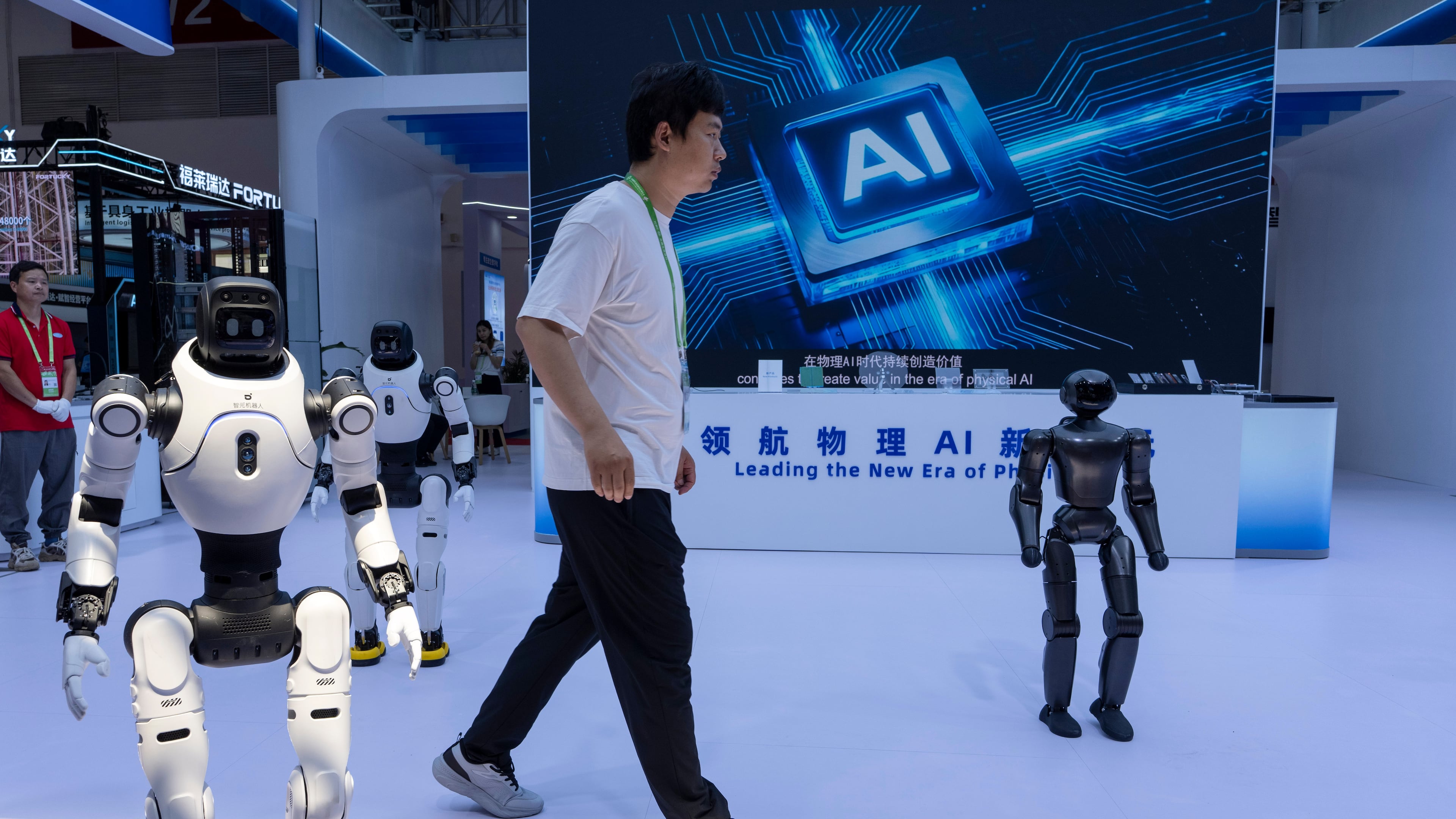 FILE- A worker passes by robots from Chinese company Lens at the China International Supply Chain Expo in Beijing on Monday, June 22, 2026. (AP Photo/Ng Han Guan, File)