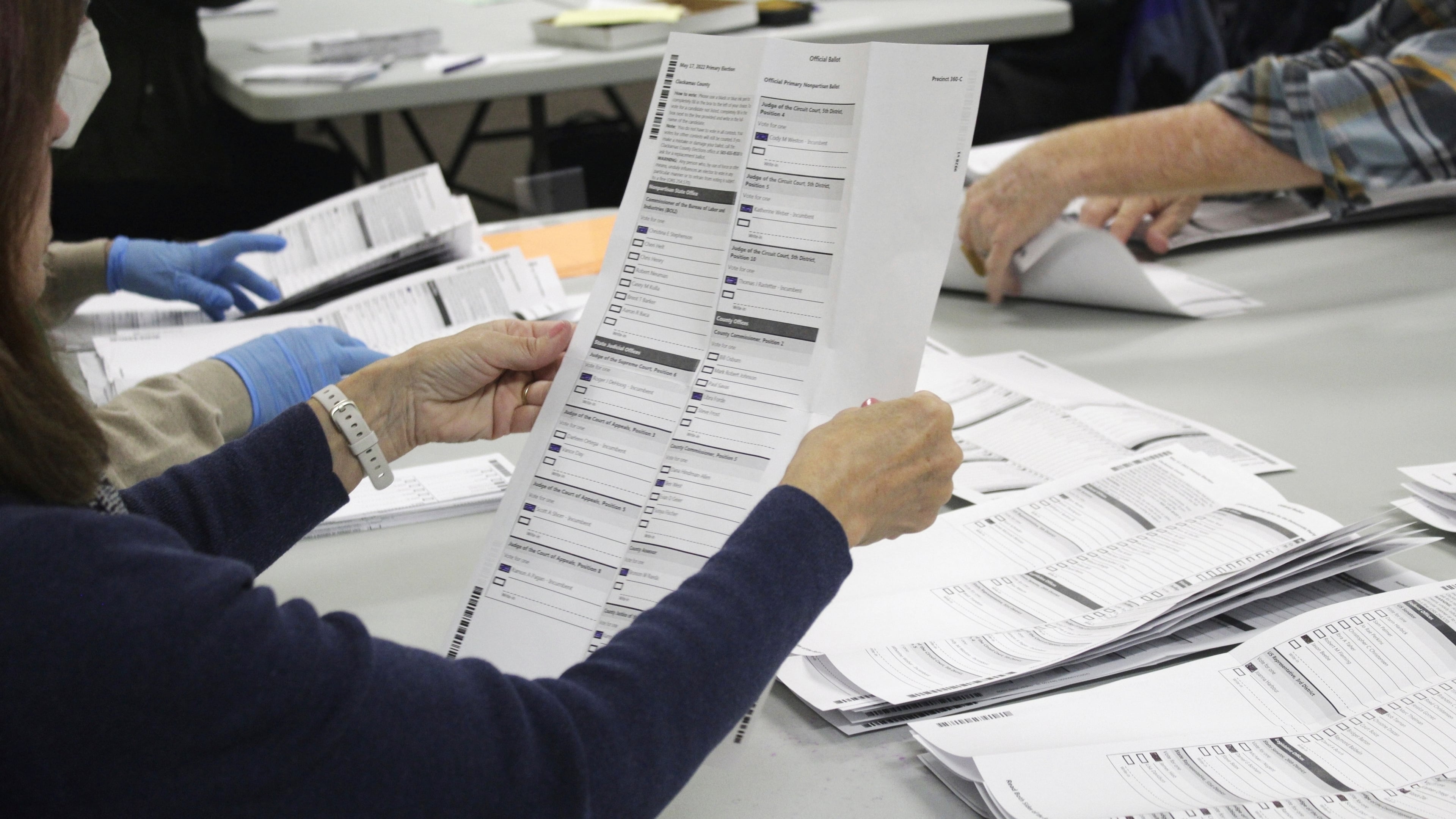 FILE - An election worker examines a ballot at the Clackamas County Elections office May 19, 2022, Oregon City, Ore. (AP Photo/Gillian Flaccus, File)