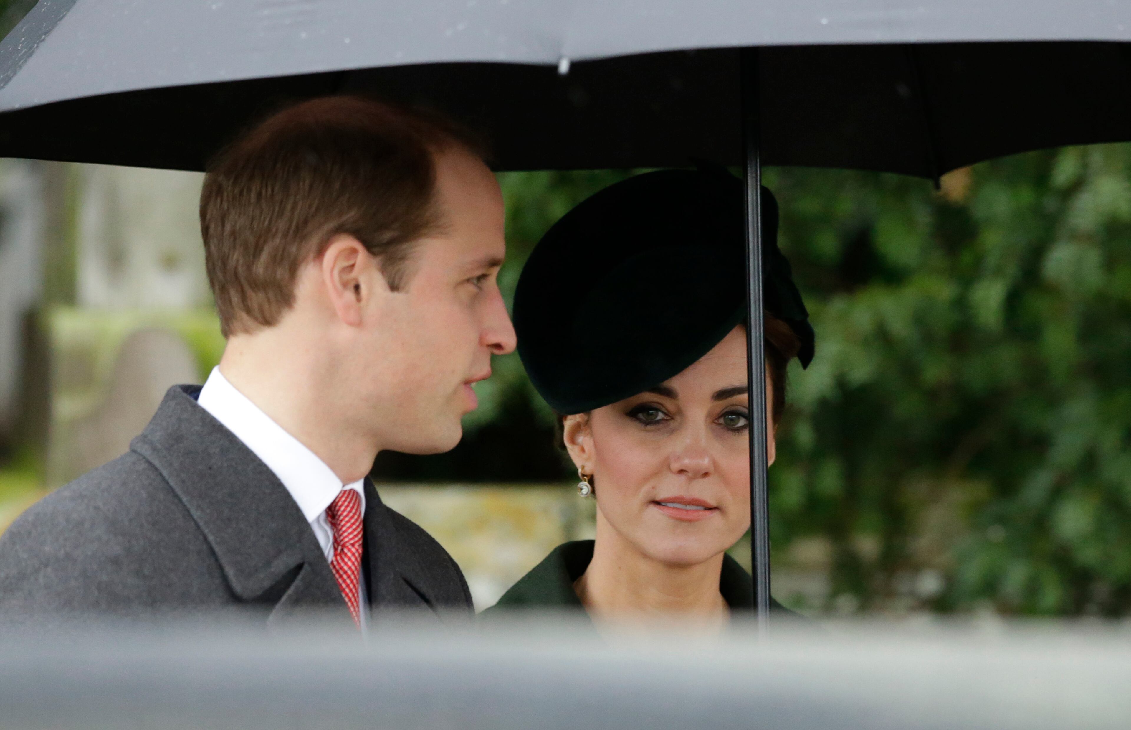 Britain's Prince William and his wife Kate the Duchess of Cambridge shelter from the rain as they leave the traditional Christmas Day church service at St. Mary Magdalene Church in Sandringham, England, Friday, Dec. 25, 2015. (AP Photo/Matt Dunham)