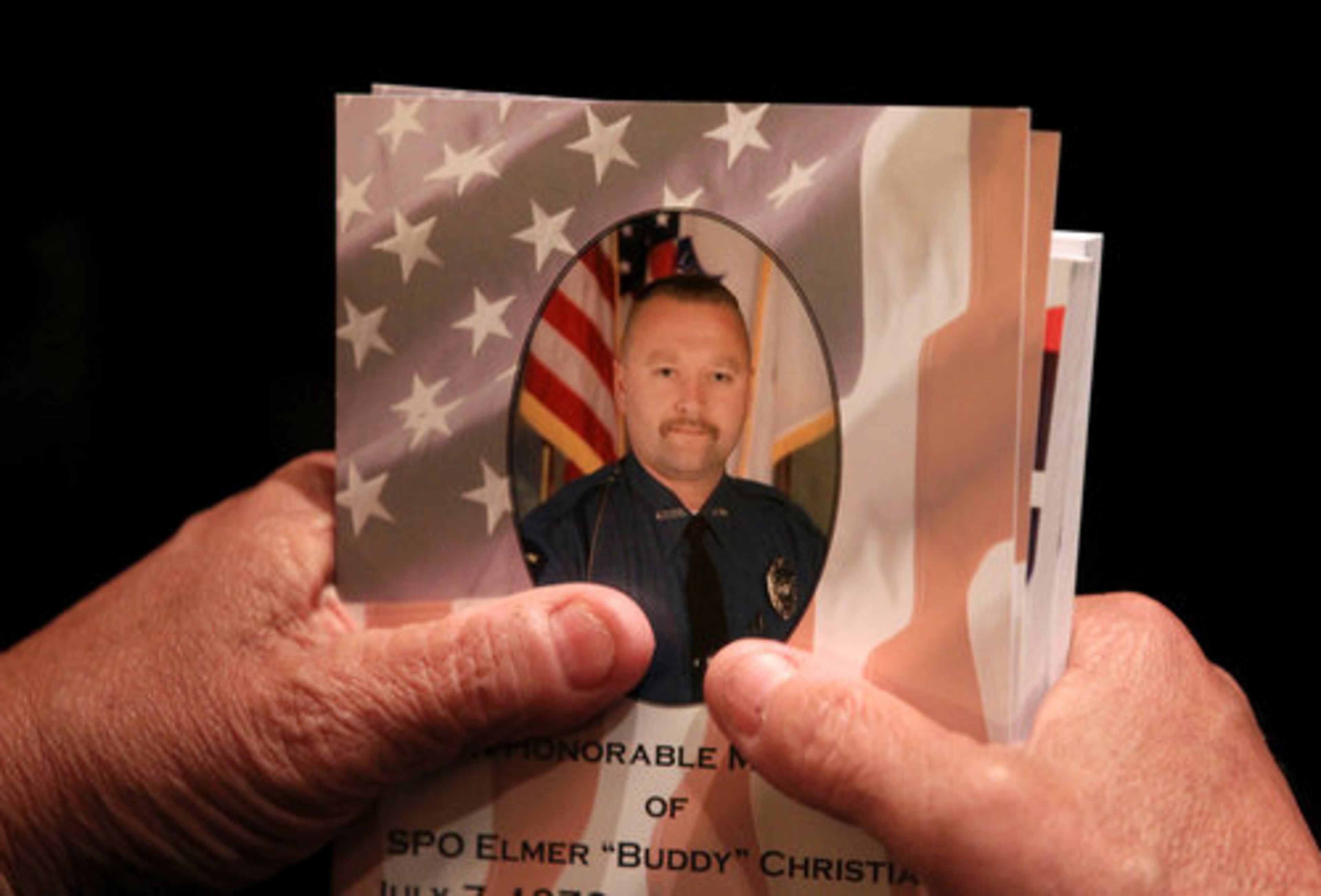 DeKalb sheriff's deputy Bruce Hood holds a memorial program during the welcome and prayer for the funeral of slain Athens Senior Officer Elmer "Buddy" Christian in the Classic Center Theatre in Athens on Sunday, March 27, 2011.