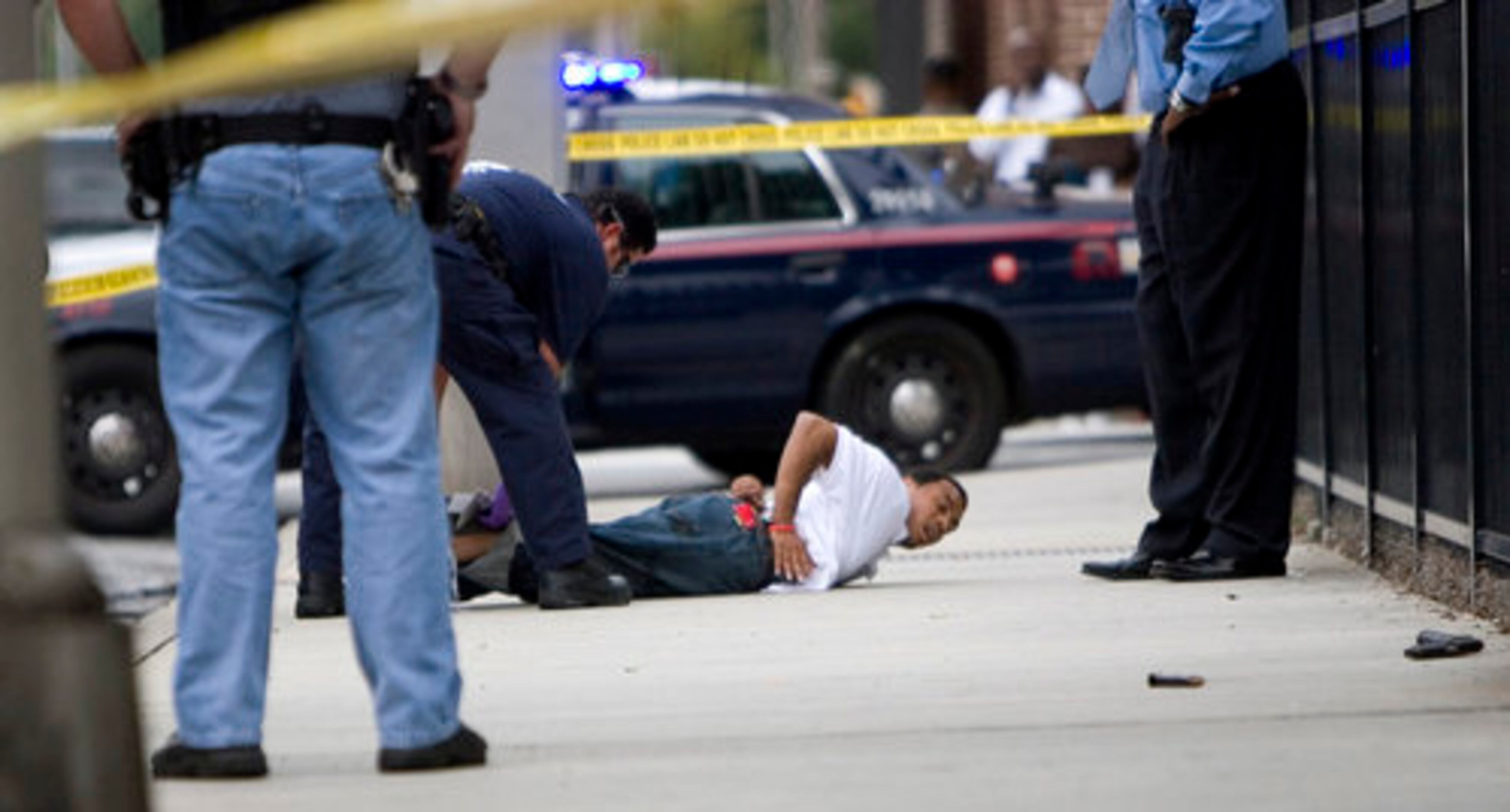 An emergency medical service worker cuts the pant leg of a suspect after he was shot in the leg and captured by police in downtown Atlanta following a chase Wednesday afternoon. A weapon can be seen on the right of this photo.