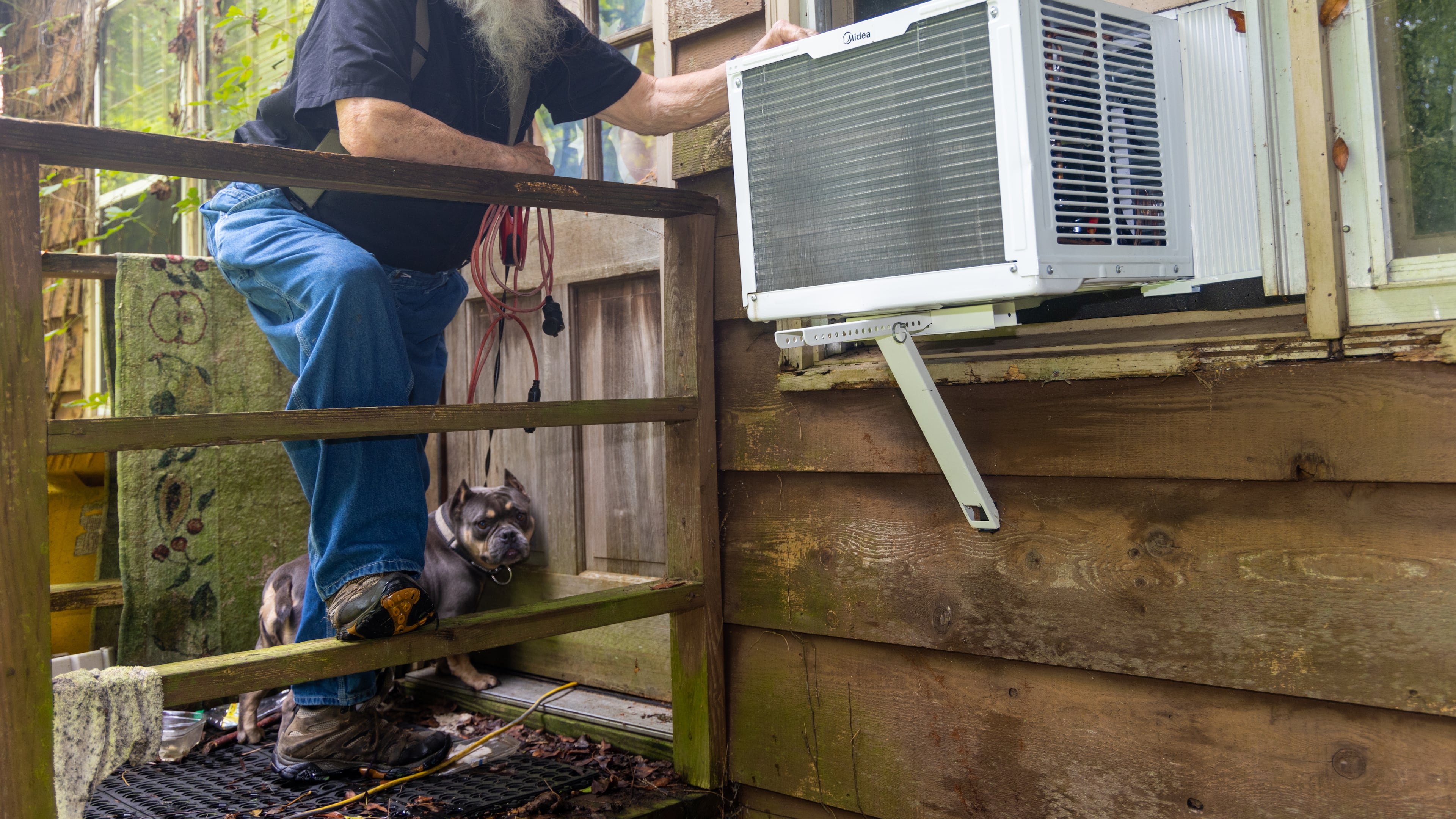 James "Rhyan" Lloyd looks at the new air conditioner in the window of his Oxford home with his dog Trinity nearby. He went to the hospital for eye surgery and was graced with a new window air conditioner after the staff learned he was living without air conditioning in the oppressive heat. PHIL SKINNER FOR THE ATLANTA JOURNAL-CONSTITUTION.