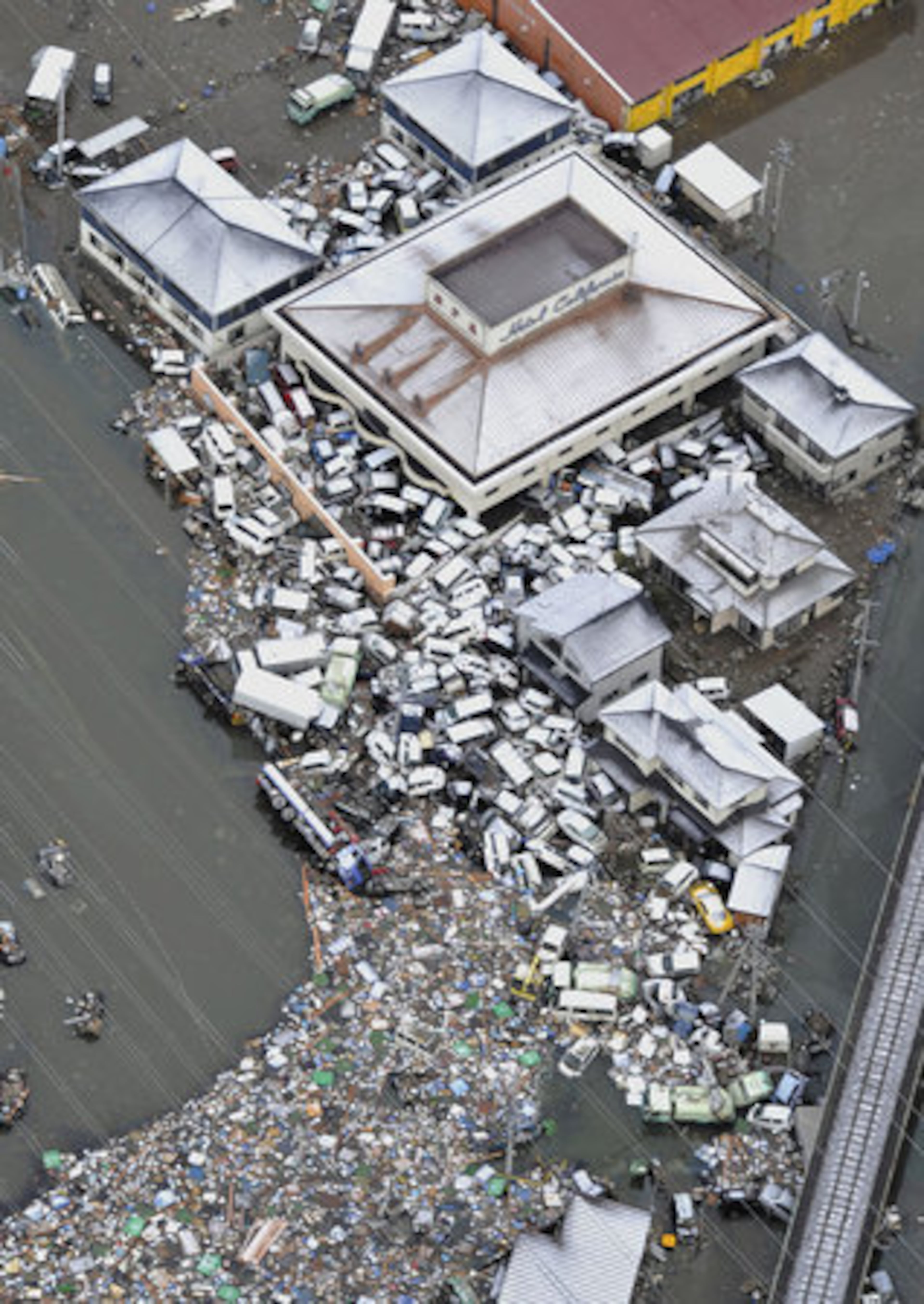 Vehicles slammed by the tsunami converge against a building in Sendai, Miyagi Prefecture, Saturday morning.