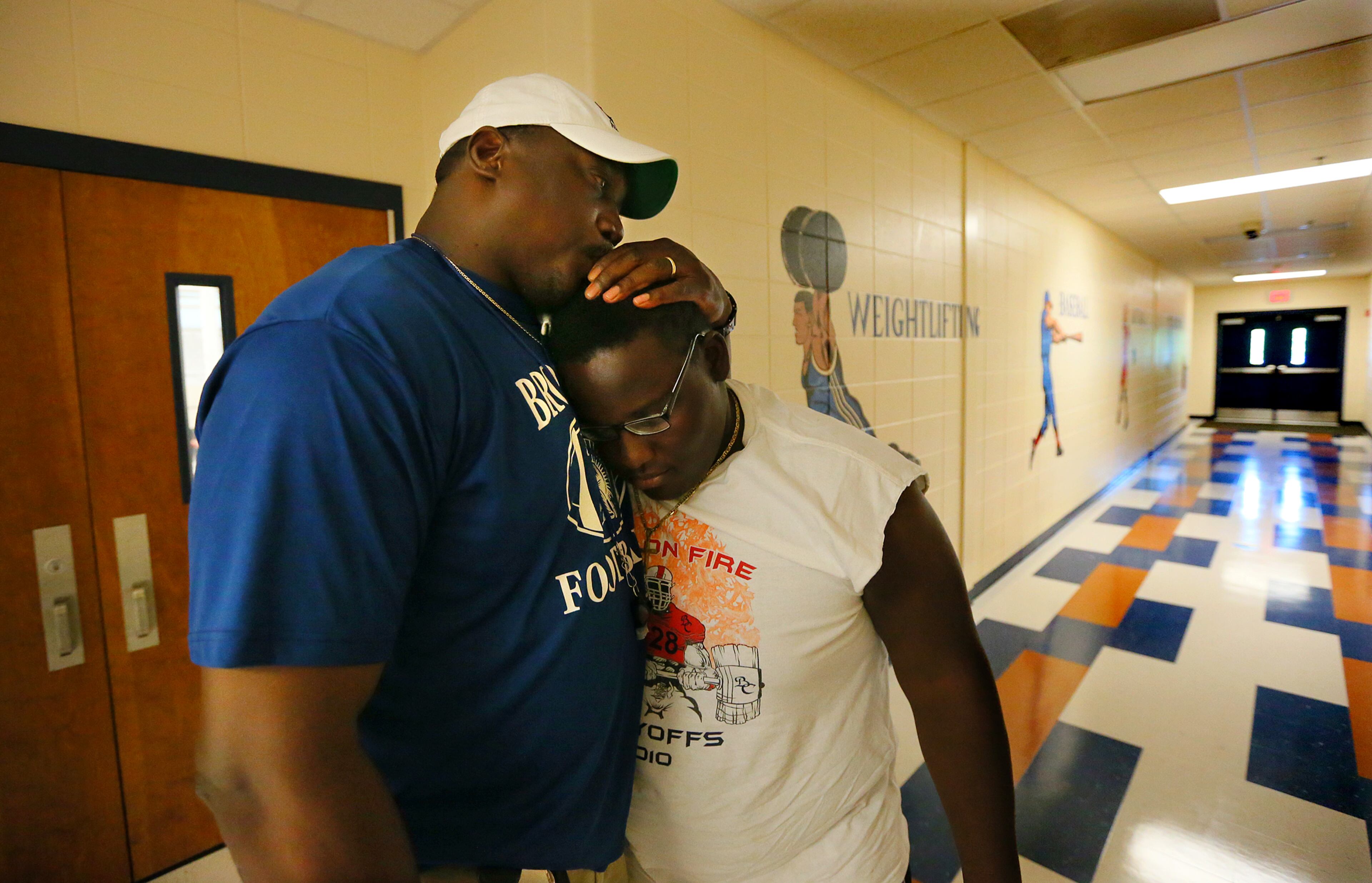Brooks County High School head football coach Maurice Freeman kisses defensive tackle Tyvon Maxwell on the head while comforting him outside his office.