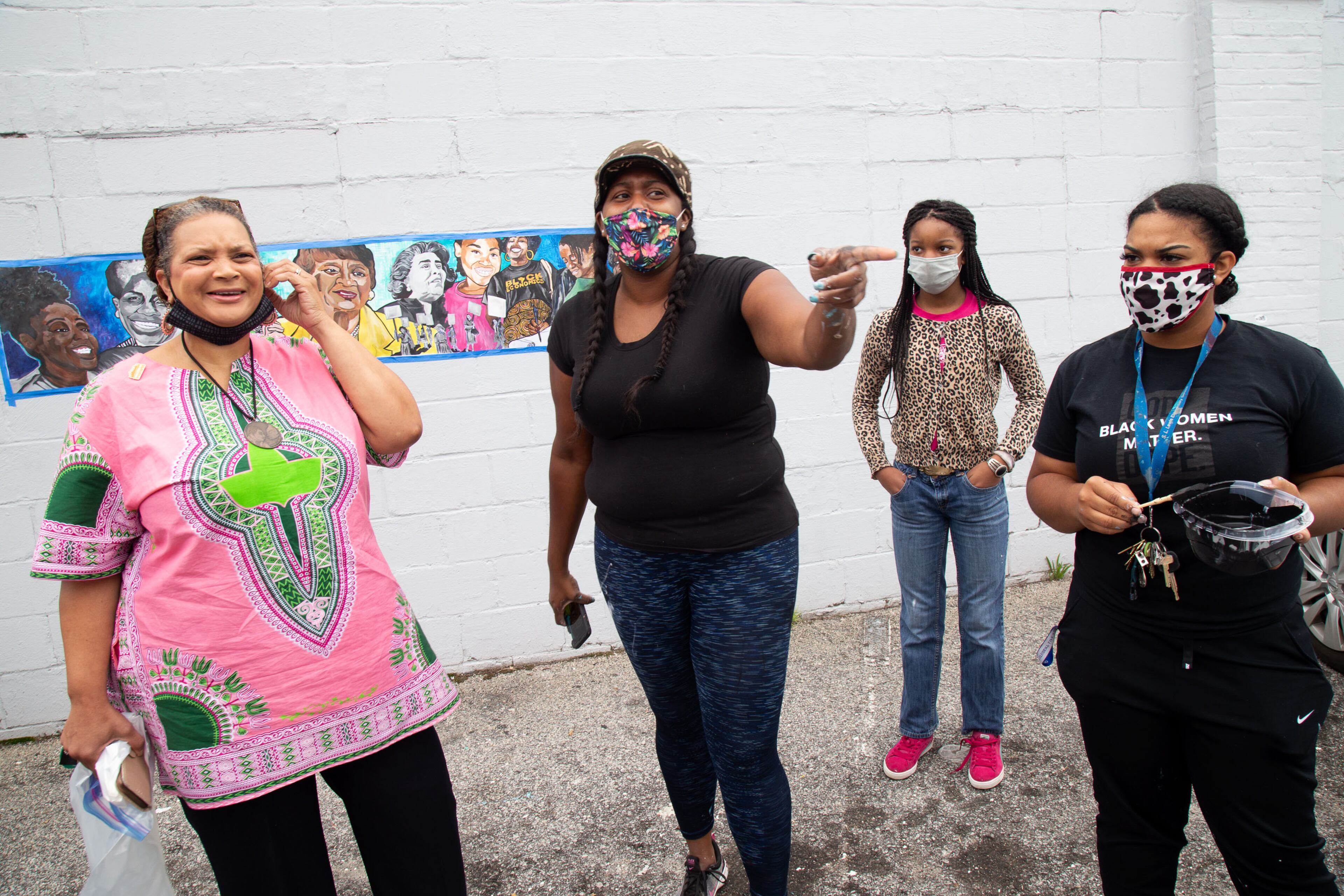 Artist Ashley Dopson (center) talks with Deborah Scott (left), executive director of Georgia Stand Up, about the "Heroine" mural Dopson is painting in Atlanta's West End. STEVE SCHAEFER / FOR THE AJC