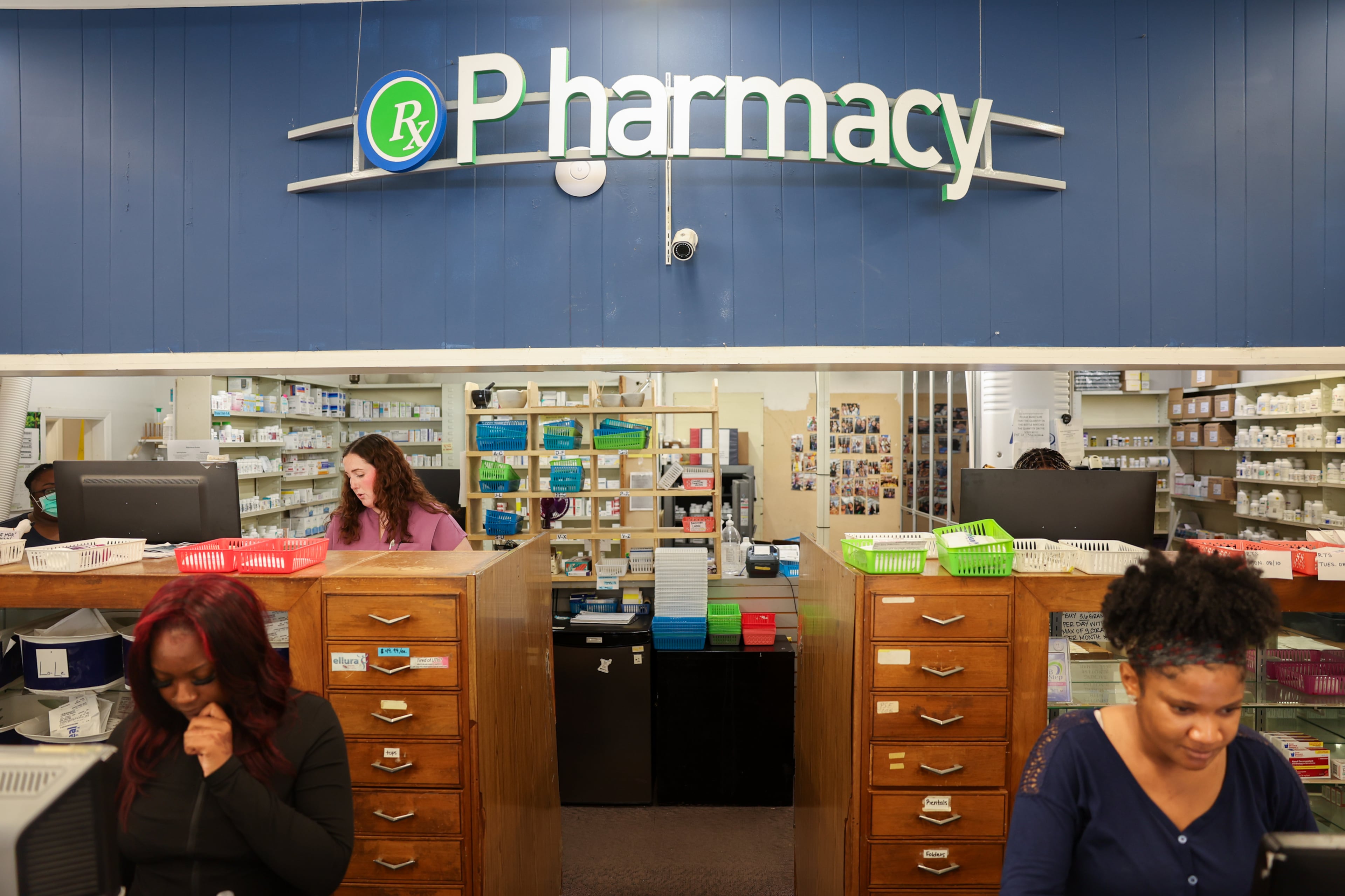 Pharmacy technicians Dylan Cheeks (foreground left) and Michelle Ola, and pharmacist Madison Coyne (back), work at Wender & Roberts Pharmacy in Atlanta on Aug. 10, 2026. The owner said it's tough to hire pharmacy techs, because many can't afford to live in Buckhead. (Arvin Temkar/AJC)