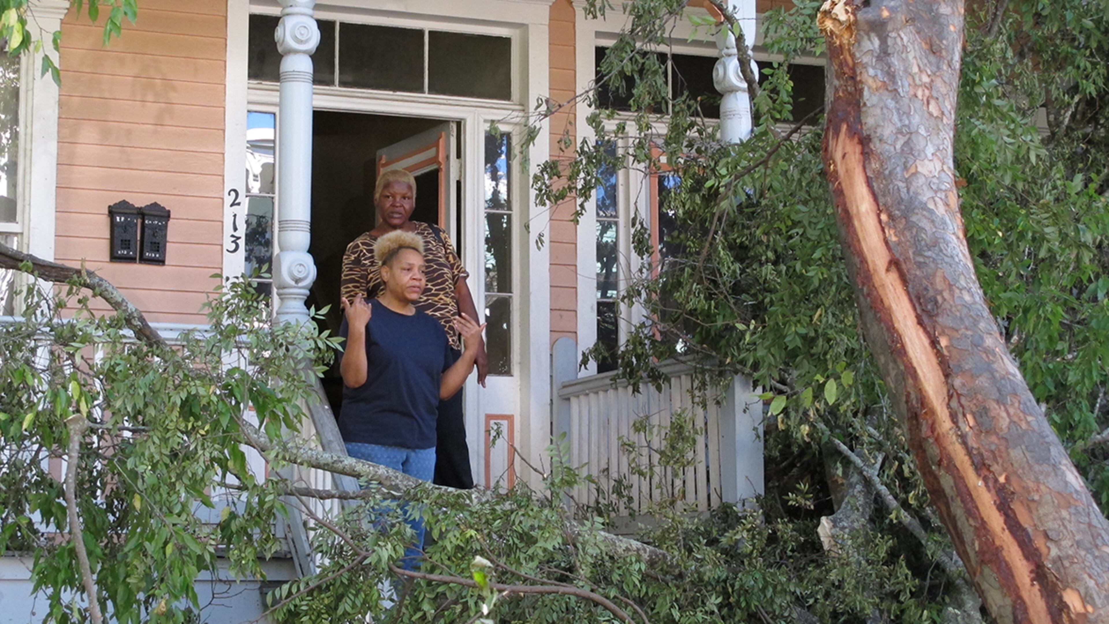 Sharon Kelsey, front, and her cousin, Pamela Williams, stand on the front port of the Victorian home in Savannah, Ga., where Kelsey lives in a first floor apartment Monday, Oct. 10, 2016. A large tree crashed across the front of the house as Hurricane Matthew raked the Georgia coast over the weekend. Matthew did extensive damage to the signature tree canopy in Savannah. (AP Photo/Russ Bynum)