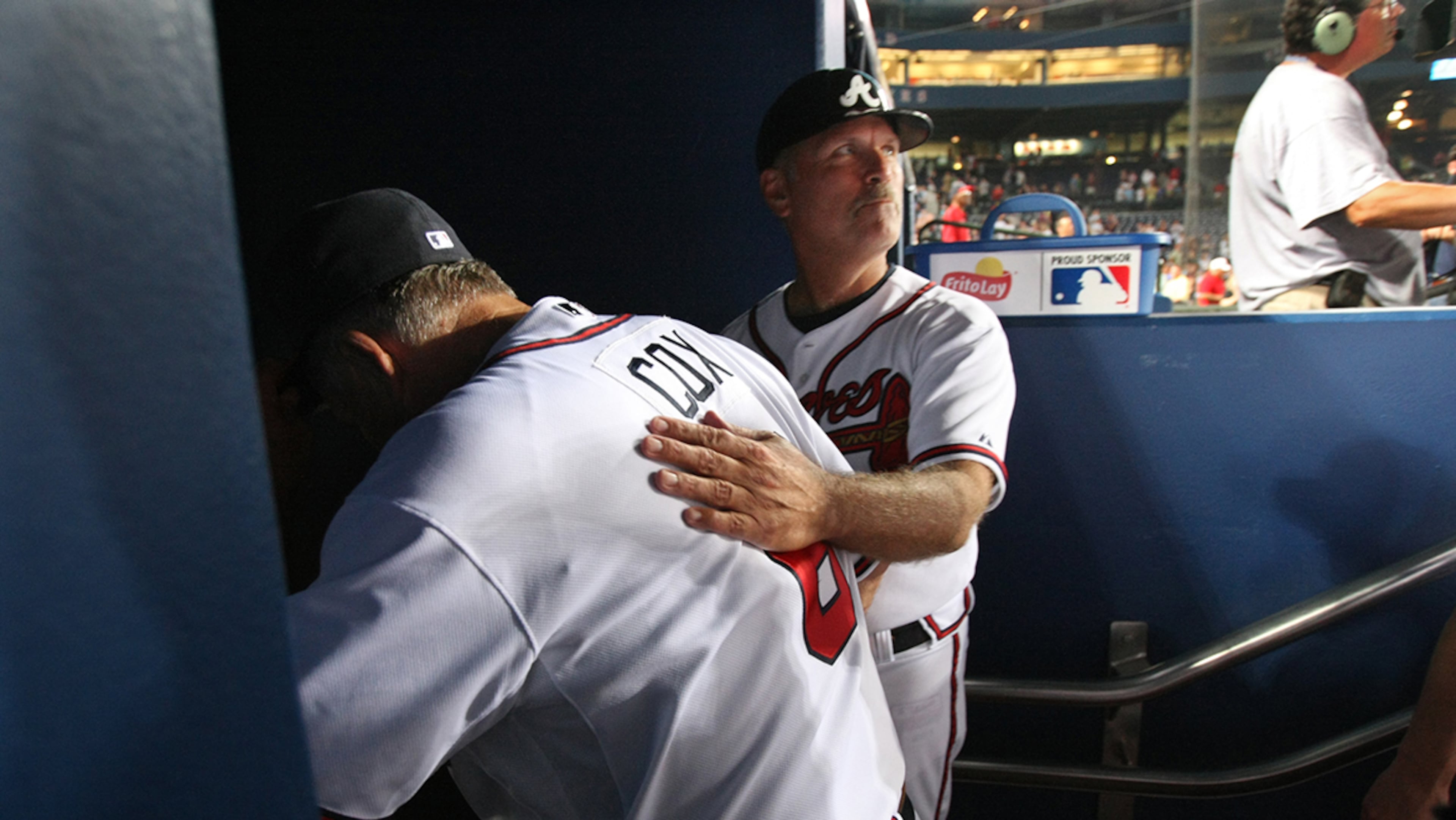 Braves coach Brian Snitker, right, pats manager Bobby Cox on the back as he quietly leaves the dugout after his 2,000th victory with the Braves on June 8, 2009. (Curtis Compton/ AJC file)