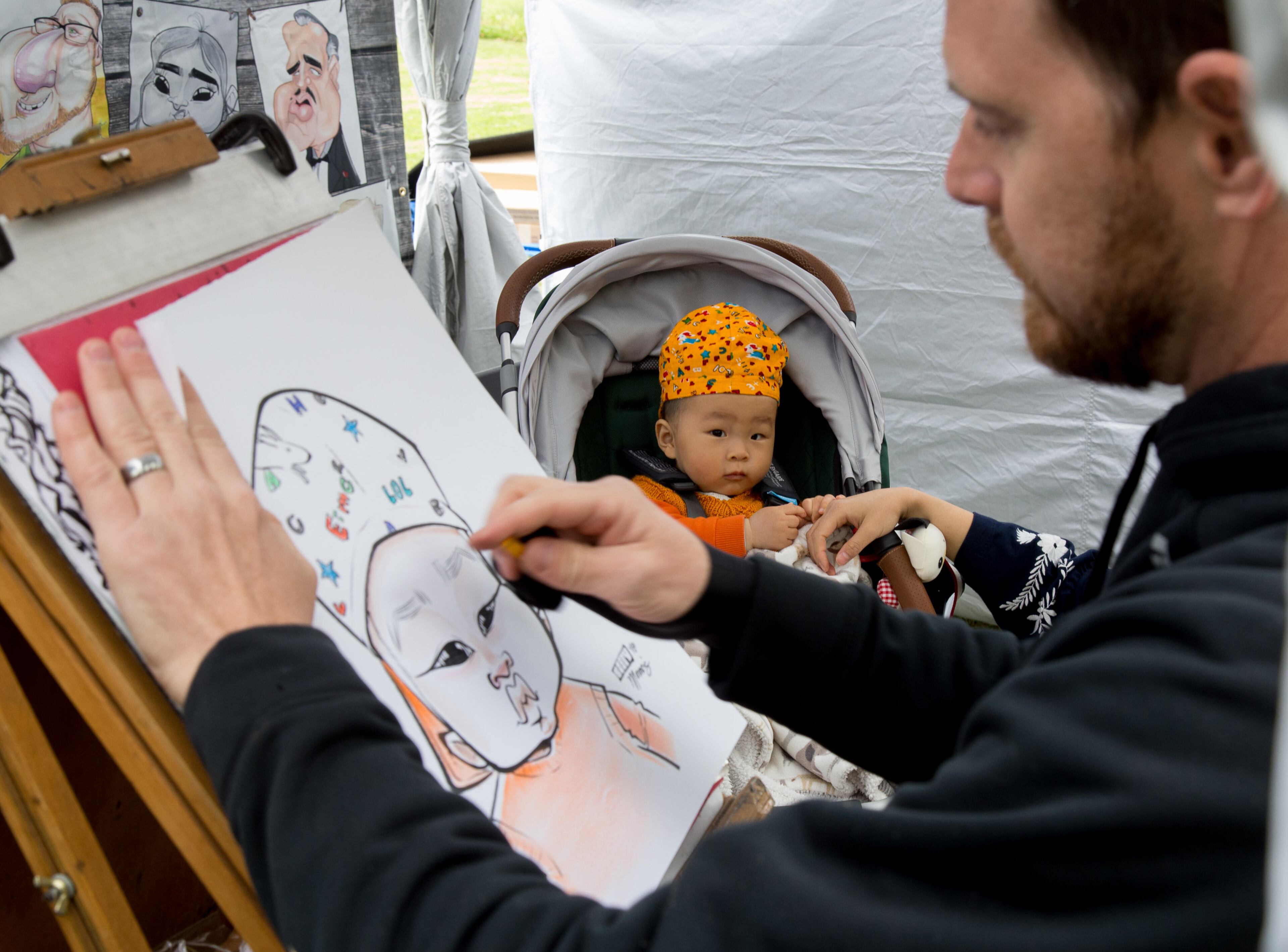 Artist Bobby Morris draws Nolan Shen's portrait during The Festival on Ponce in Atlanta GA Sunday, April 8, 2018. STEVE SCHAEFER / SPECIAL TO THE AJC