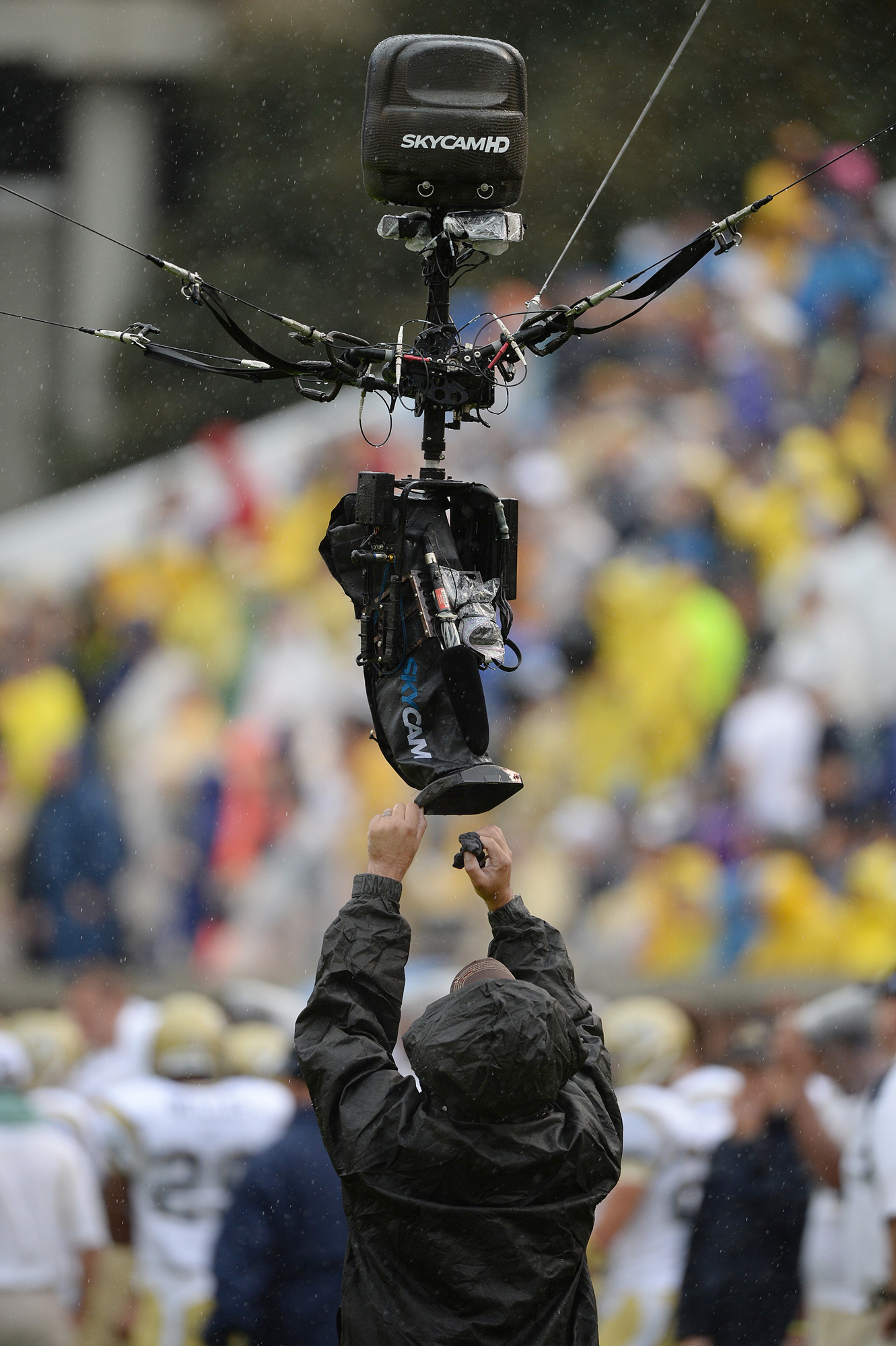 An ESPN cameraman wipes the water off the lens of the remote camera inside Bobby Dodd Stadium during Georgia Tech vs North Carolina football game on Saturday, September 21, 2013.