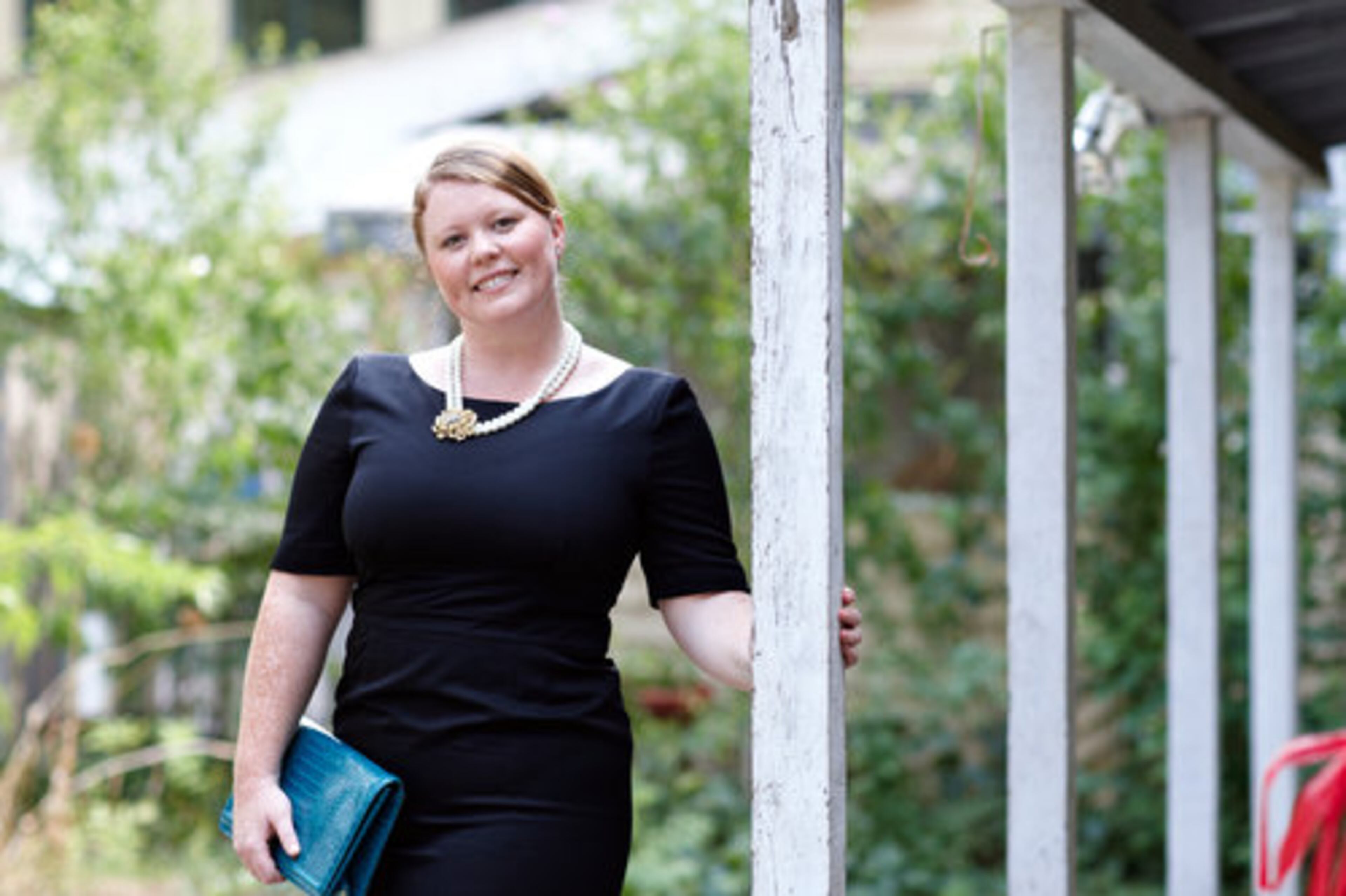 Baber wears a black bateau neck suit dress from J. Crew. She accessorizes with a turquoise snake skin print clutch from Banana Republic, a strand of pearls and a vintage broach from Antiques & Beyond.