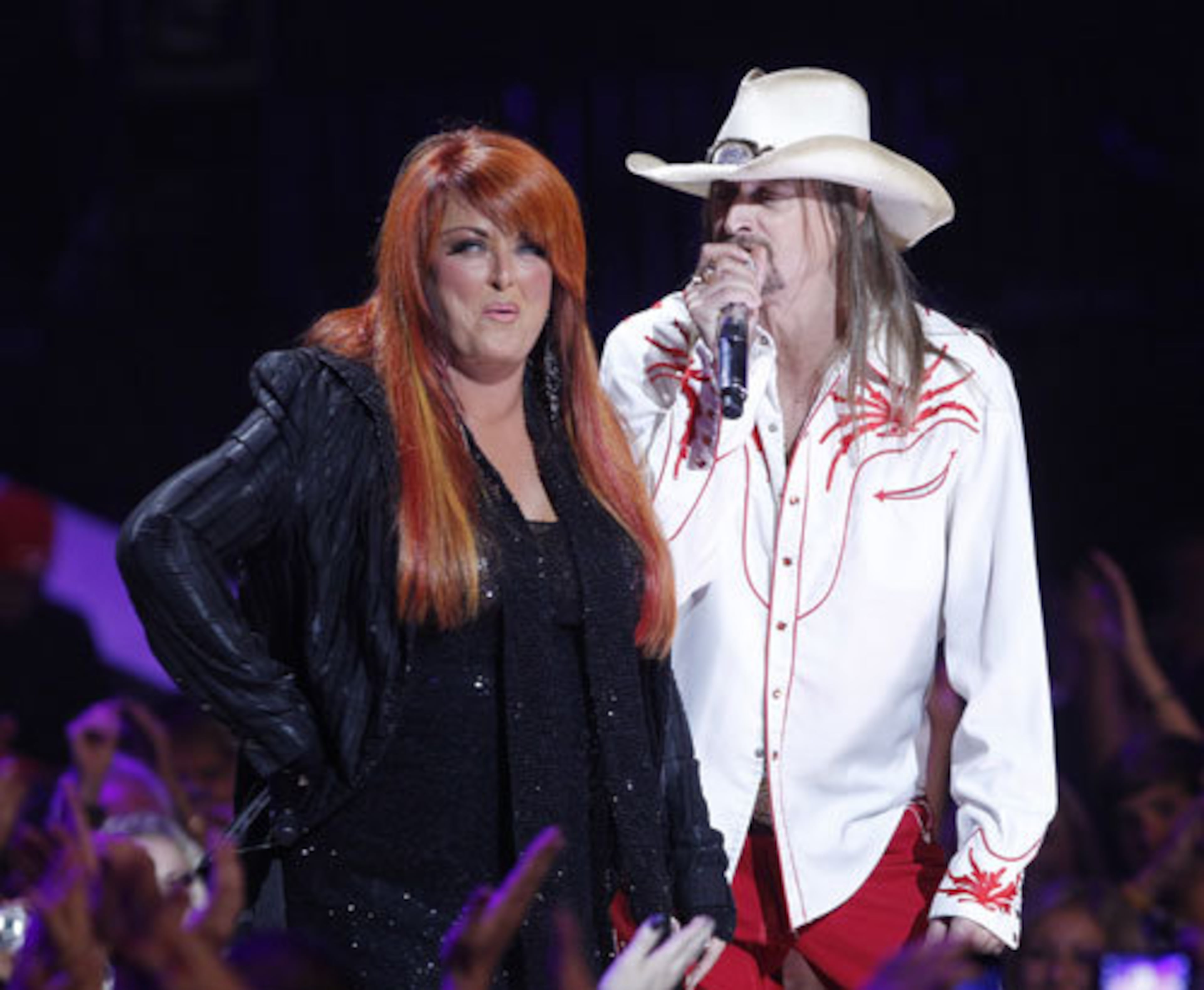 Wynonna Judd plays coy with Kid Rock on stage.