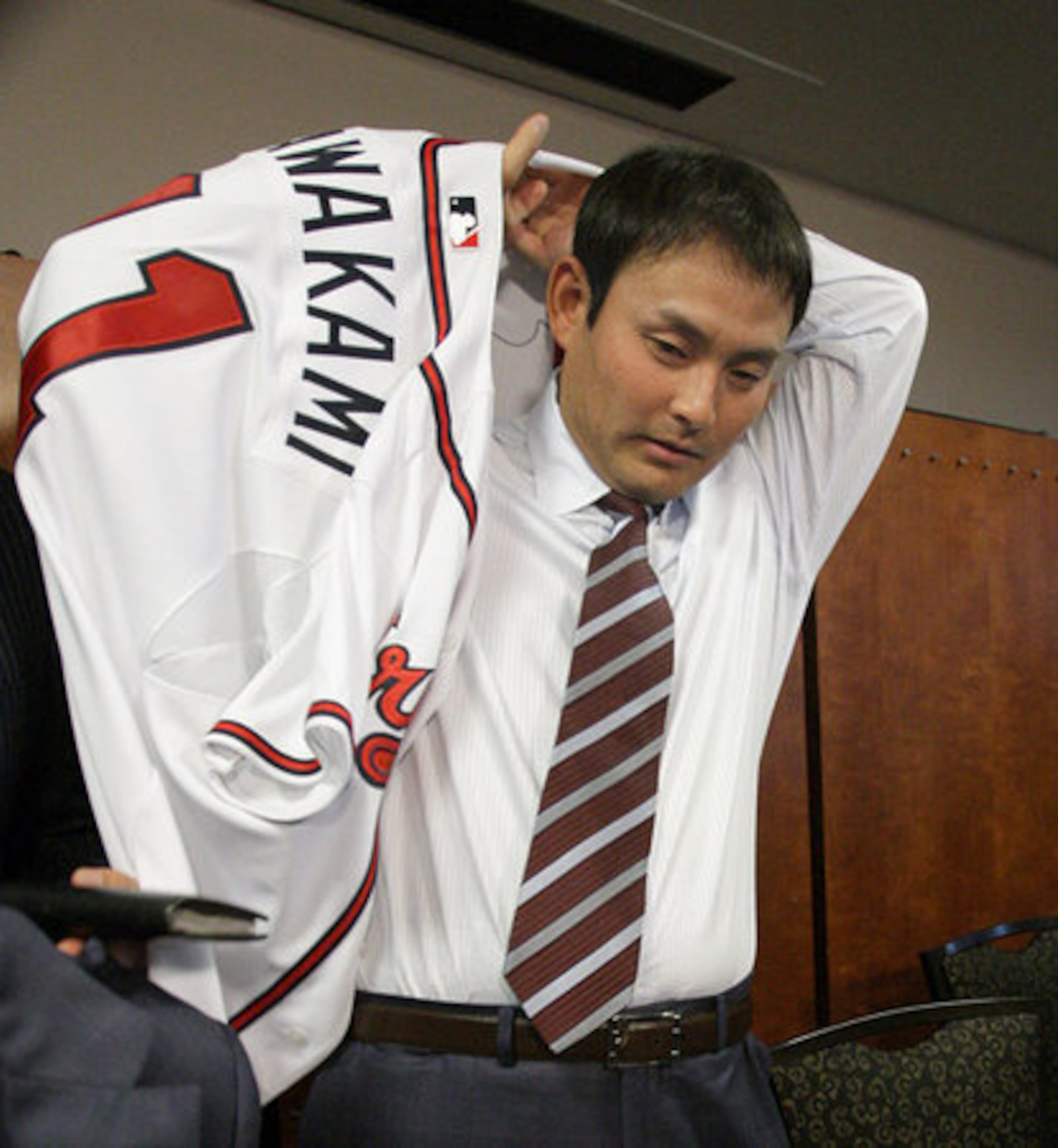 New Braves pitcher Kenshin Kawakami tries on his No. 11 Braves jersey for the first time as he is introduced to the Atlanta press corps. The Japanese star agreed to a three-year, $23 million free-agent contract with the Braves on Saturday.