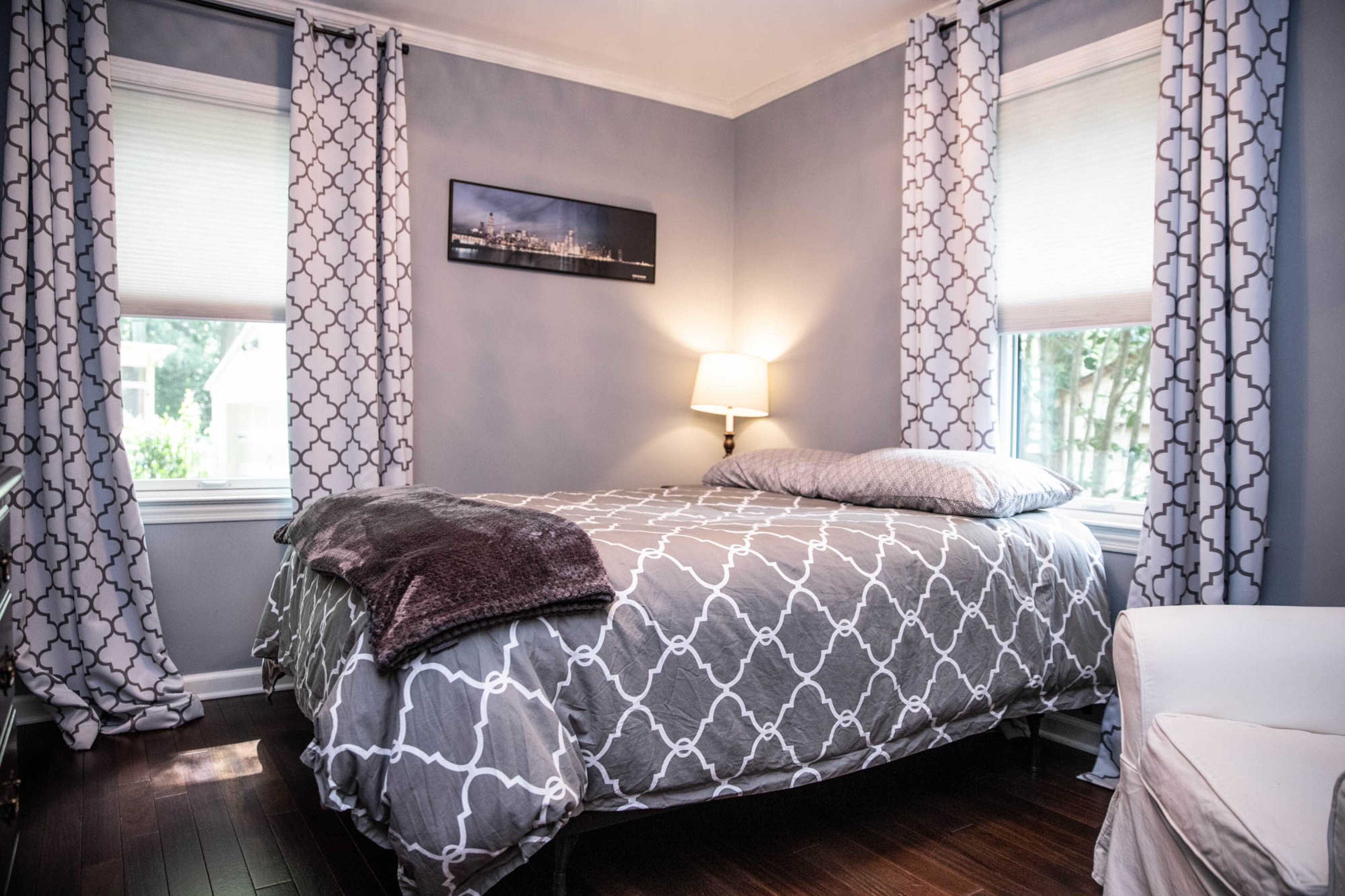 Cityscapes of Chicago and Boston - the cities in which homeowners Ben Ratossa and Adam Perry grew up - hang on opposite walls in the guest room of their DeKalb County home. A quatrefoil print on the bedspread and curtains creates a cohesive, cozy look.