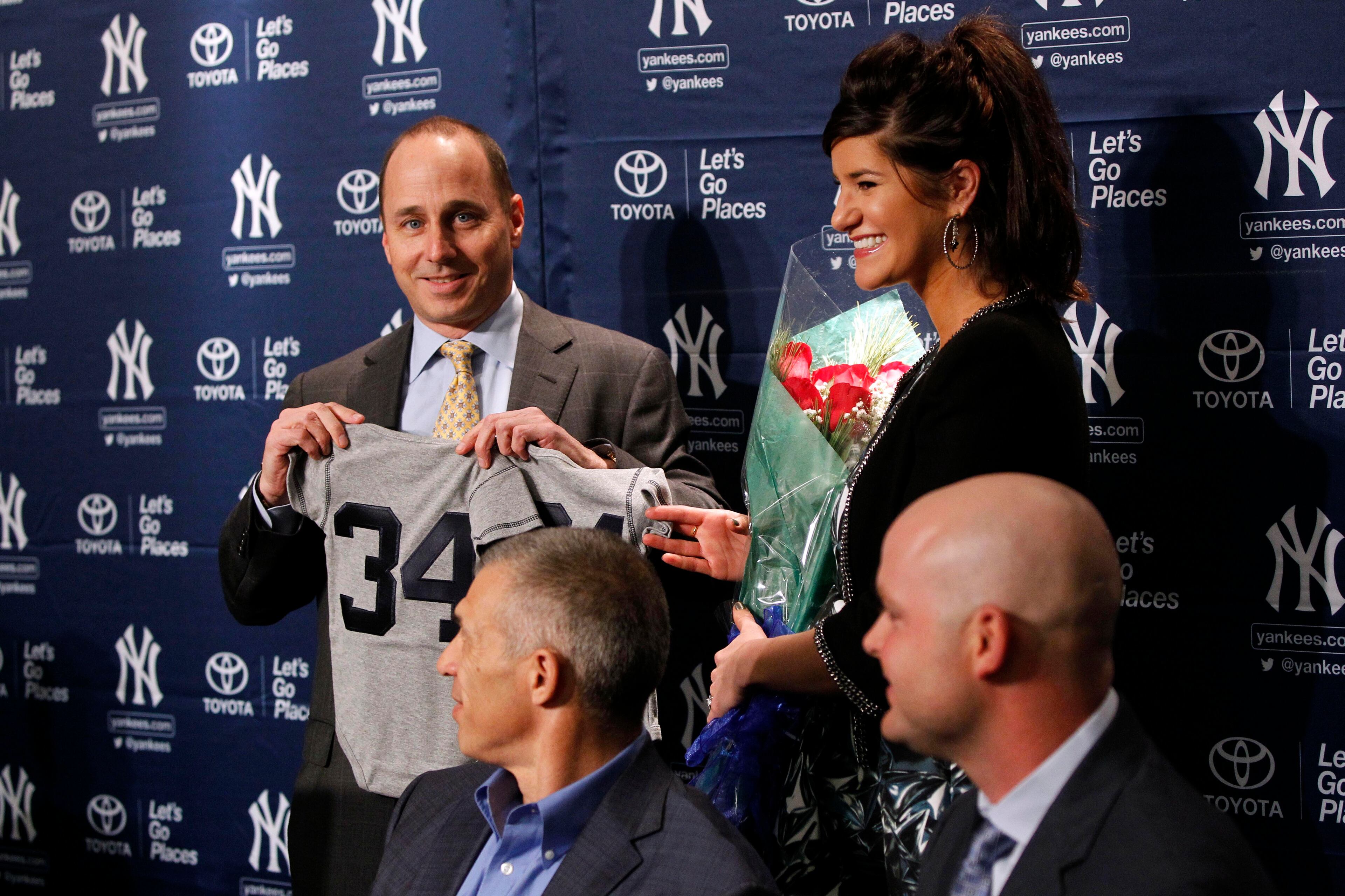 Yankees general manager Brian Cashman presents a tee shirt for the McCann children to Ashley McCann.
