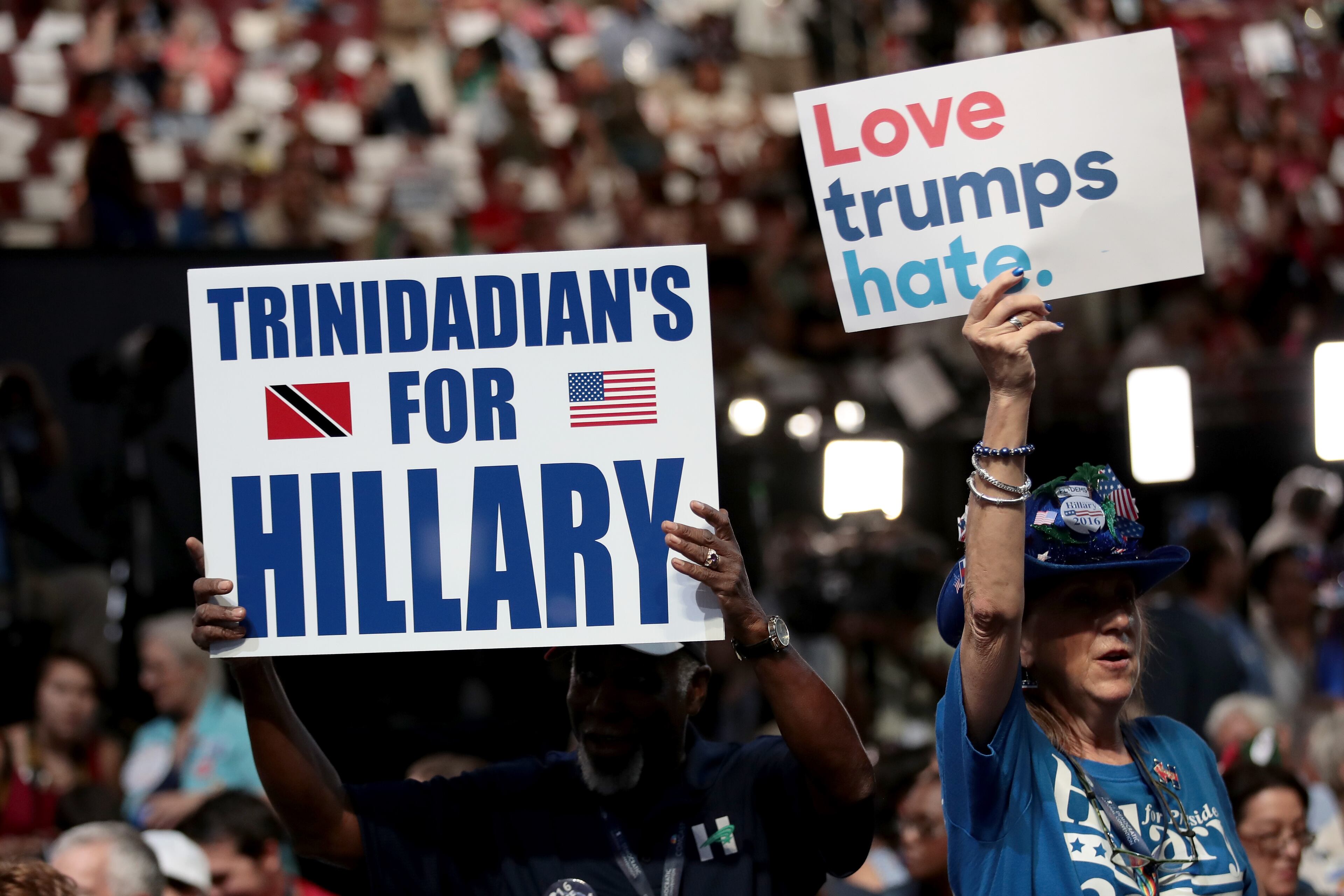 Delegates hold up signs that read "Love trumps hate" and Trinidadian's For Hillary" on the first day of the Democratic National Convention at the Wells Fargo Center, July 25, 2016 in Philadelphia, Pennsylvania. An estimated 50,000 people are expected in Philadelphia, including hundreds of protesters and members of the media. The four-day Democratic National Convention kicked off July 25. (Photo by Drew Angerer/Getty Images)