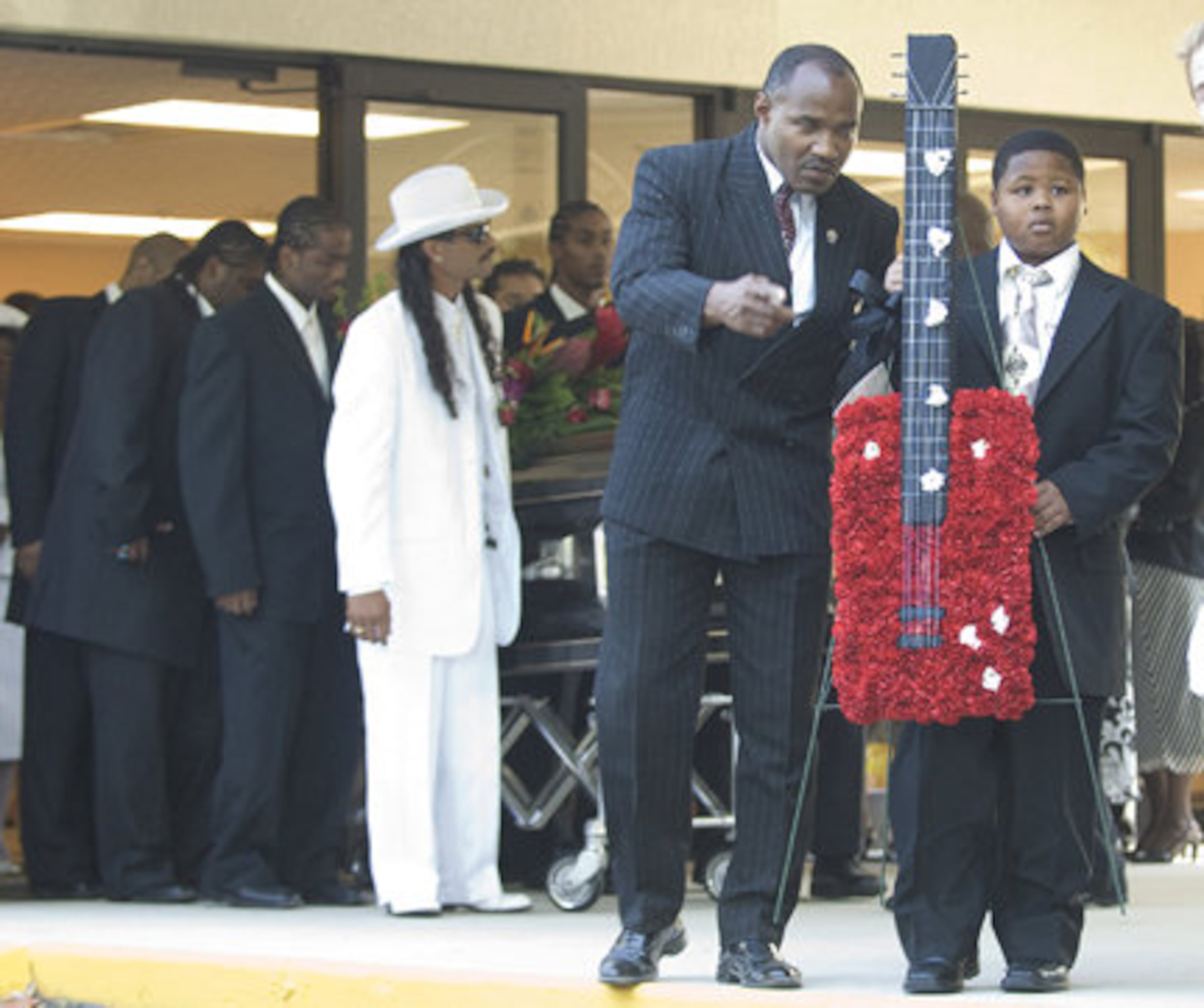 A young boy carries a floral wreath shaped as a guitar as the casket of Bo Diddley is carried from the funeral home in Gainesville.