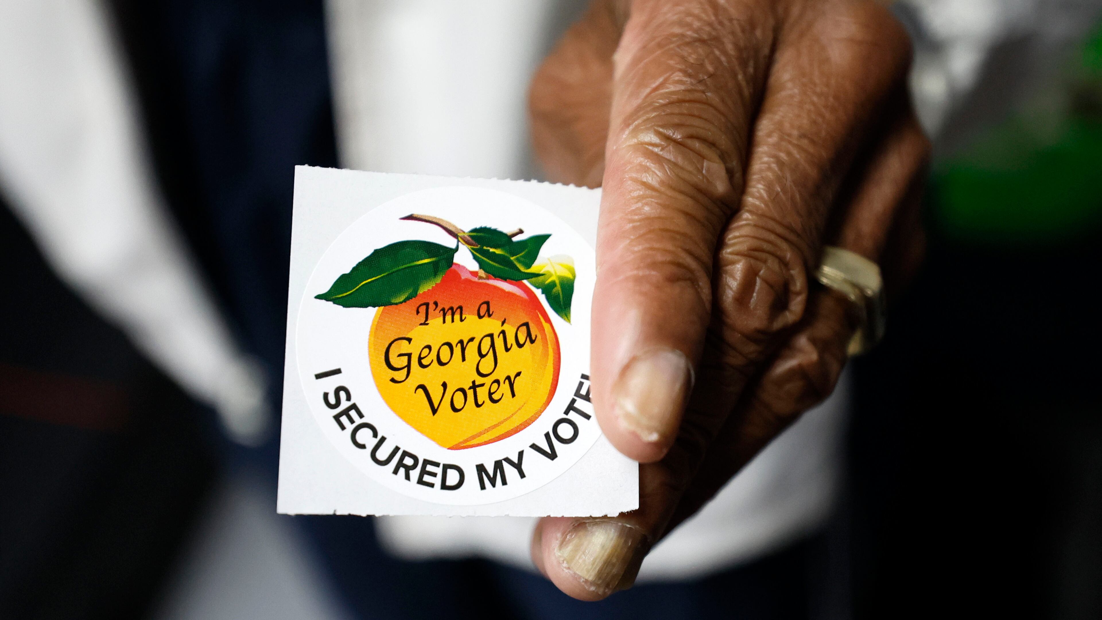 A poll worker holds a Georgia voter sticker ready to be handed to a voter at Berean Christian Church on Oct. 17, 2022. (Miguel Martinez/The Atlanta Journal-Constitution)