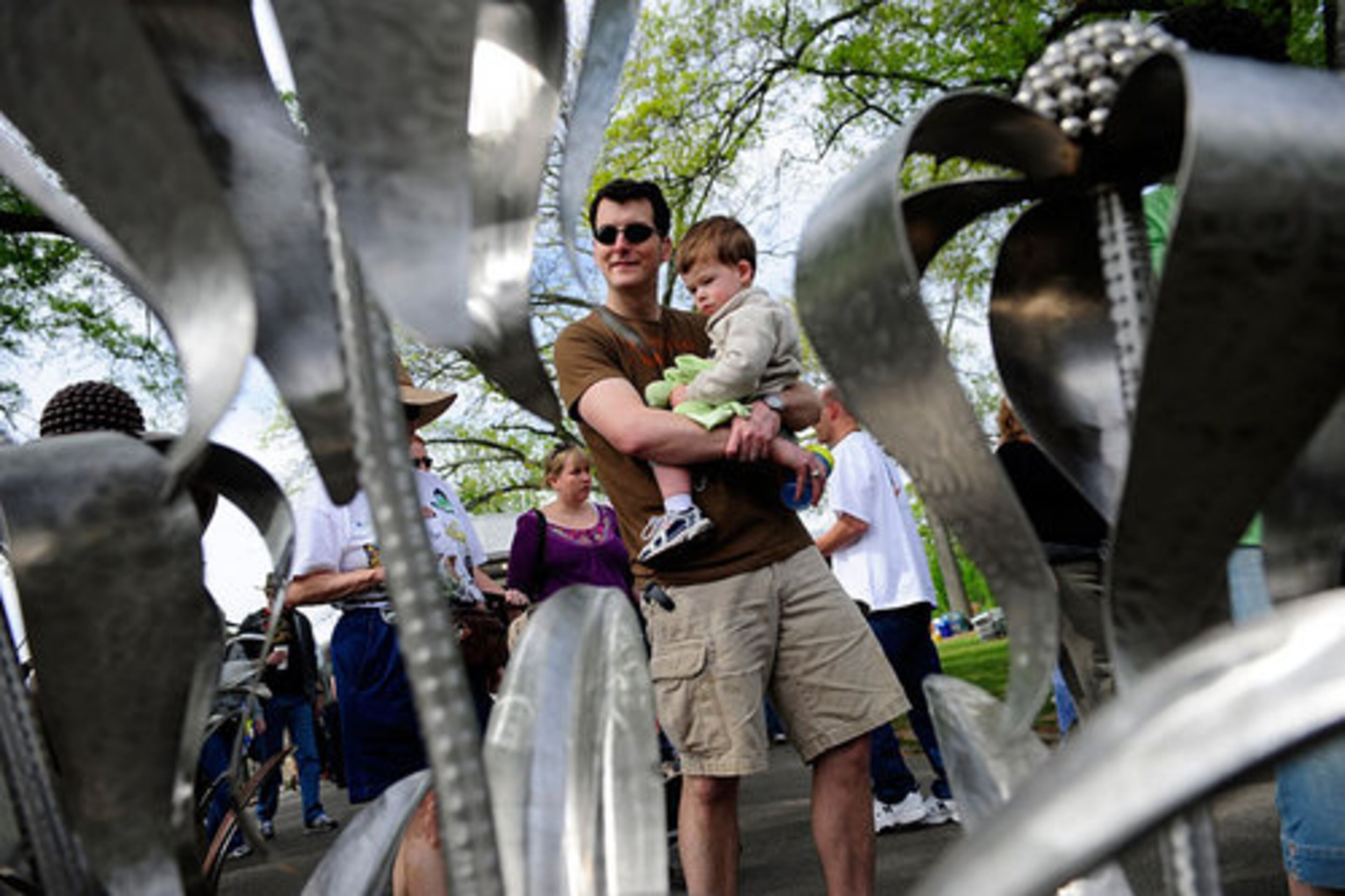 James Farquharson, 35, carries his 2-year-old son Alex past oversized iron flowers. Farquharson, of Decatur, said he was glad the event returned to Piedmont Park.