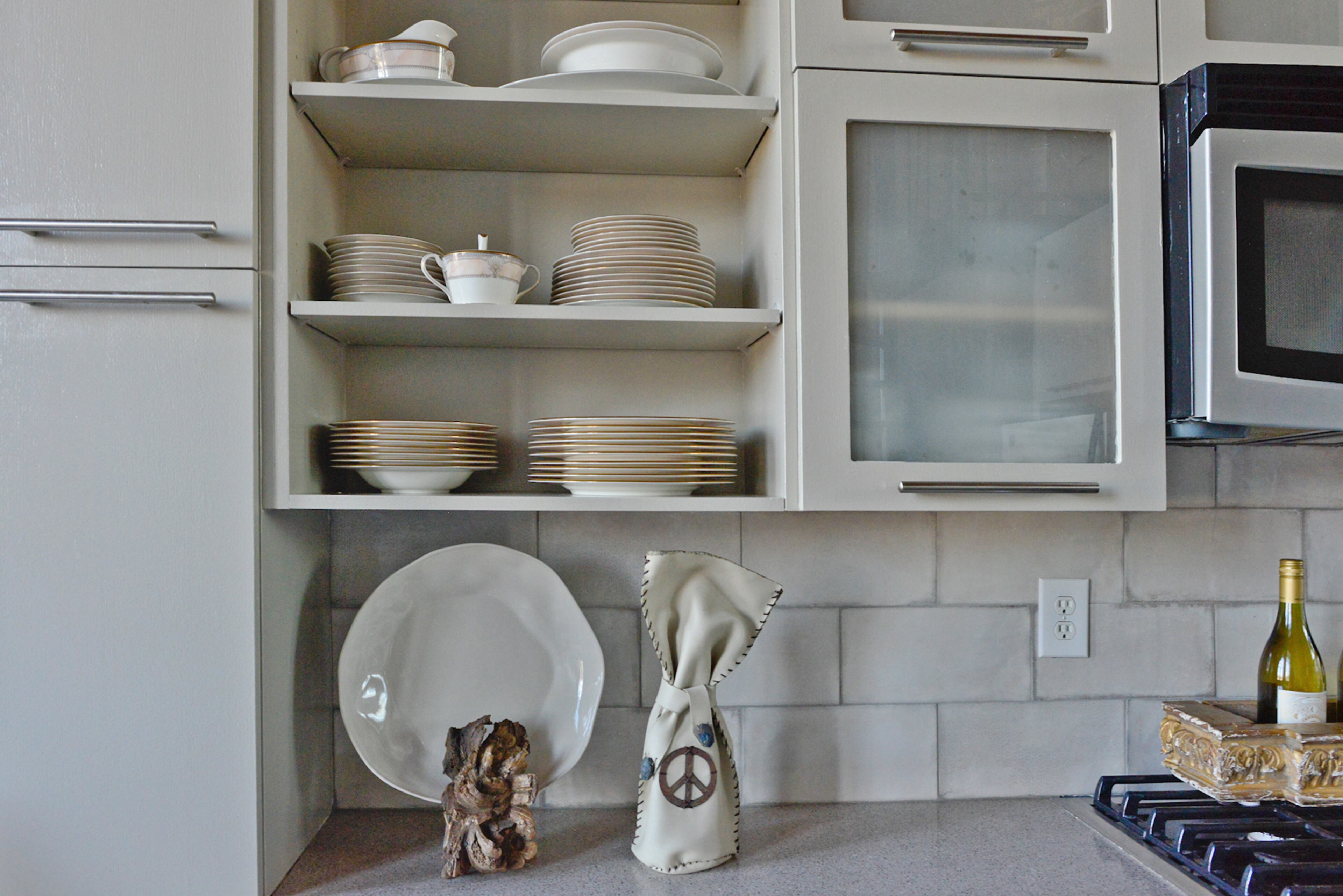 Open kitchen shelves display china while the ceramic tile backsplash fits with the vintage industrial design of the Atlanta loft in a building dating to the 1880s.