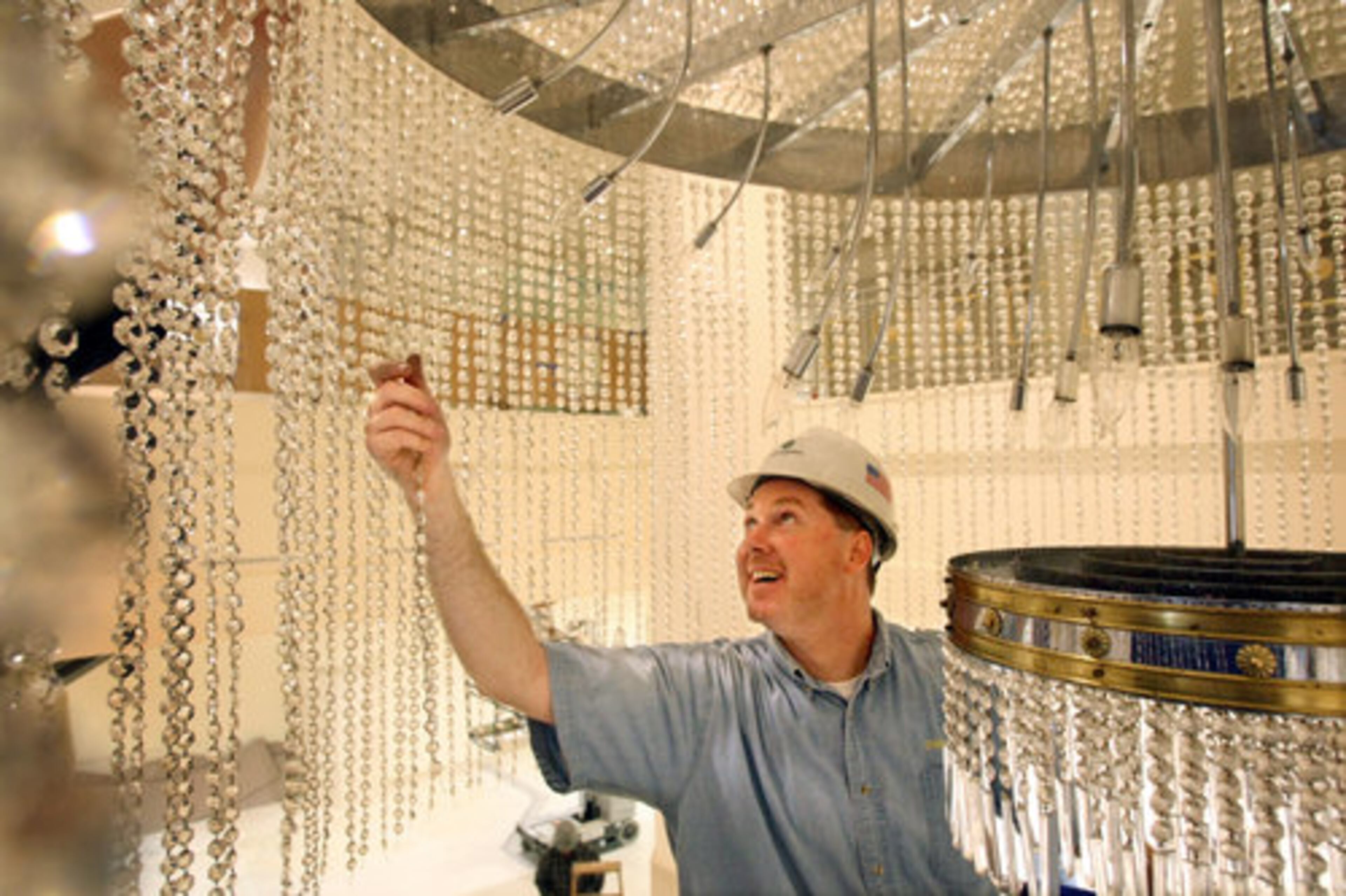 Chandelier Specialists owner Mike Lee re-pins strands of crystals.