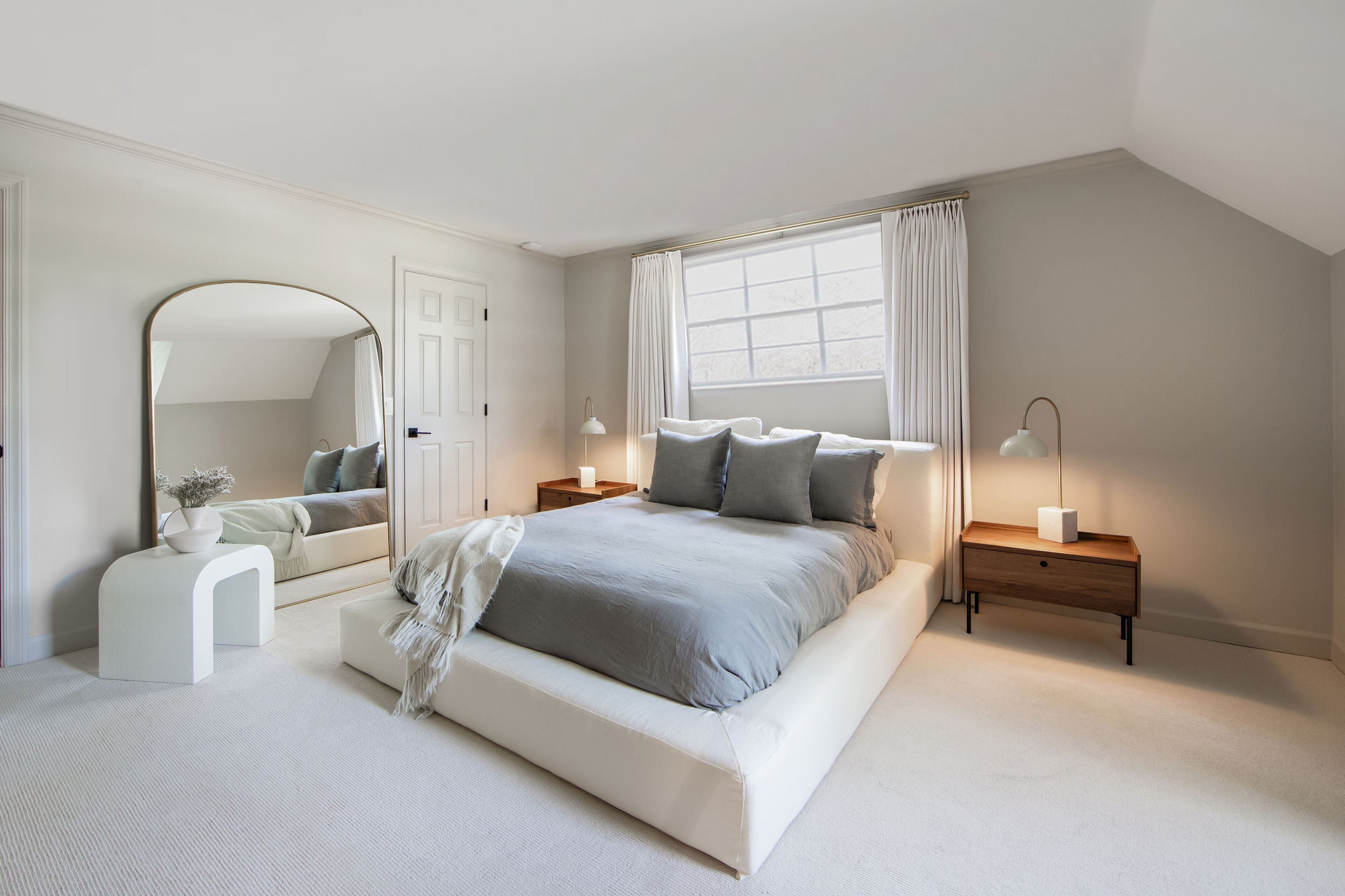 This quiet guest room is bathed in neutrals, from the plush Restoration Hardware bed frame to the soft carpeting underfoot. The large floor mirror from Rejuvenation breaks up the large space, while the waterfall table next to it continues the theme of soft curves. Text by Lori Keong/Photo by Amanda Winchester