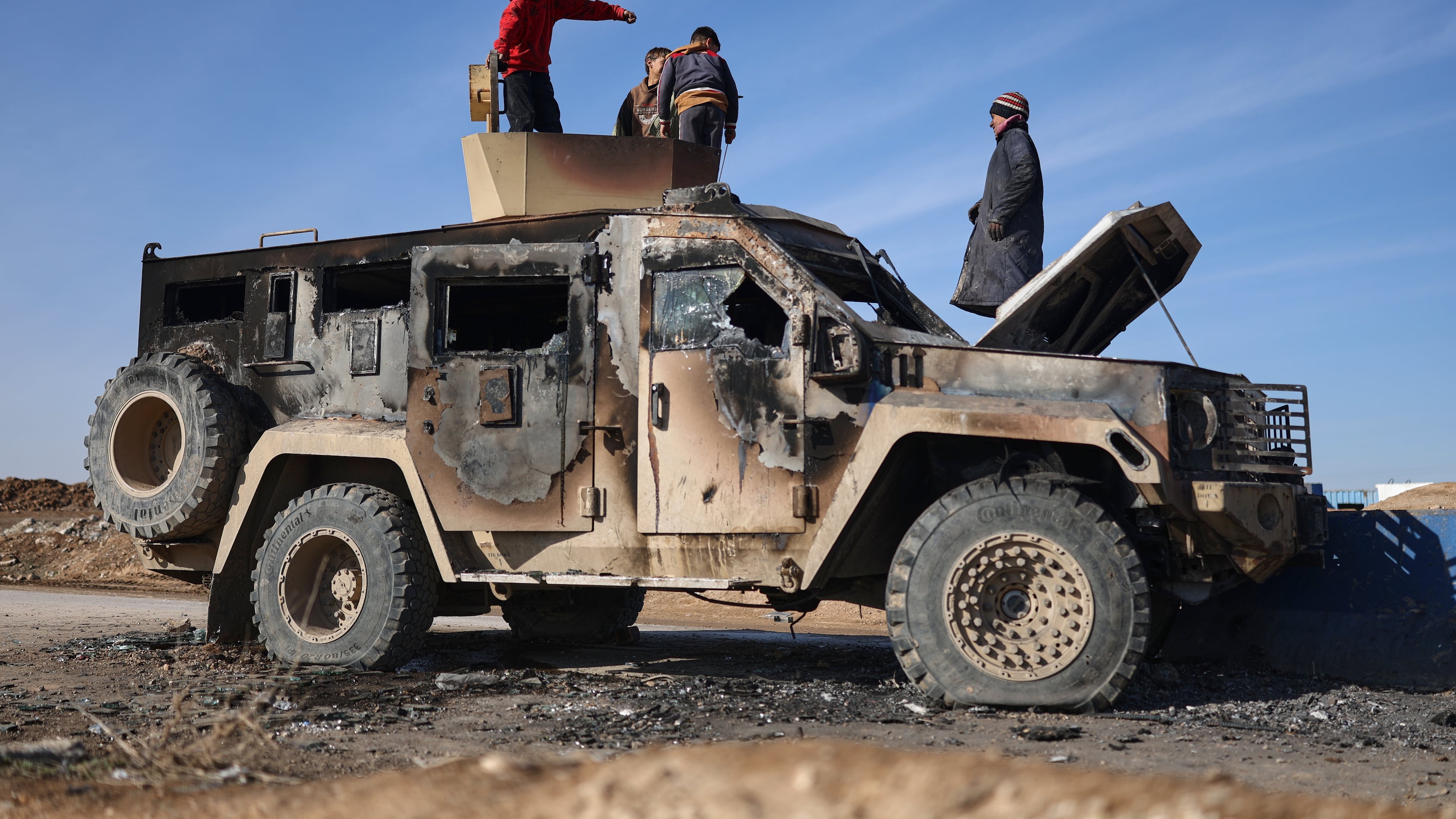 Local youth play atop of a damaged armored vehicle belonging to the Syrian Democratic Forces (SDF) at the site of clashes with Syrian government forces in the village of al-Hol in northeastern Syria's Hasakeh province, Syria, Wednesday, Jan. 21, 2026. (AP Photo/Ghaith Alsayed)