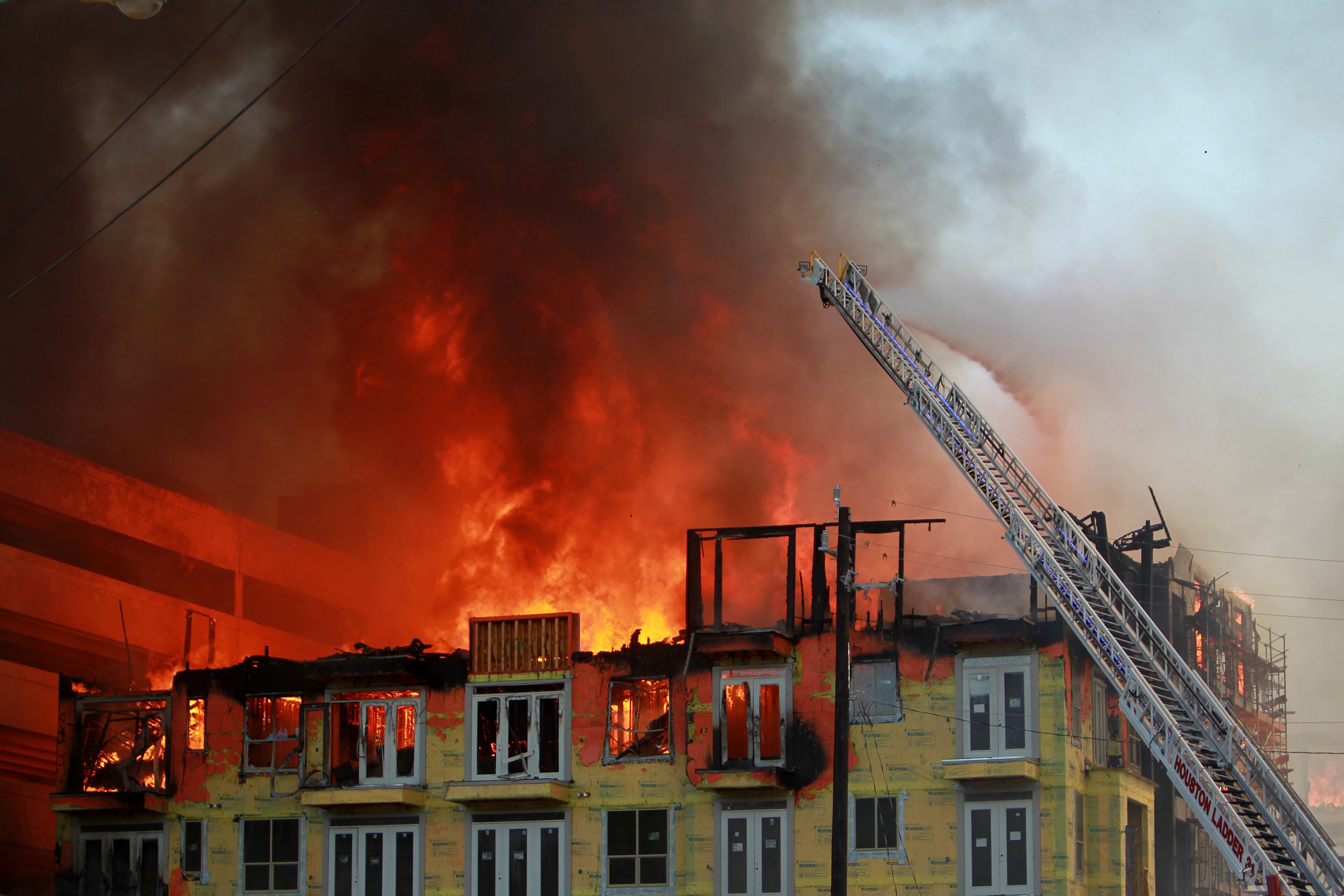 Houston firefighters spray water from atop a ladder trying to extinguish a five-alarm fire at a construction site Tuesday, March 25, 2014, in Houston. Fire officials said more than 200 emergency personnel were at the scene Tuesday afternoon and were working to protect nearby buildings. (AP Photo/Houston Chronicle, Mayra Beltran)